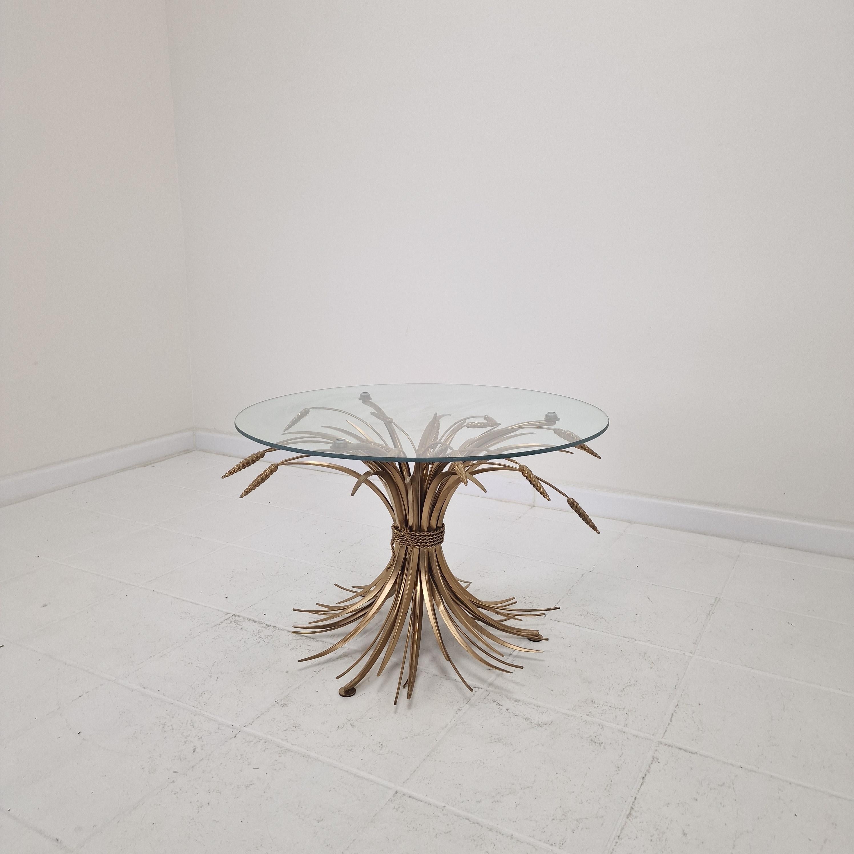 A striking Hollywood Regency-style coffee table from the 1970s, featuring a sculptural gilded “Sheaf of Wheat” base — an iconic motif made famous by Coco Chanel, who used a similar piece in her Paris apartment.

The wheat sheaf design, finished in a