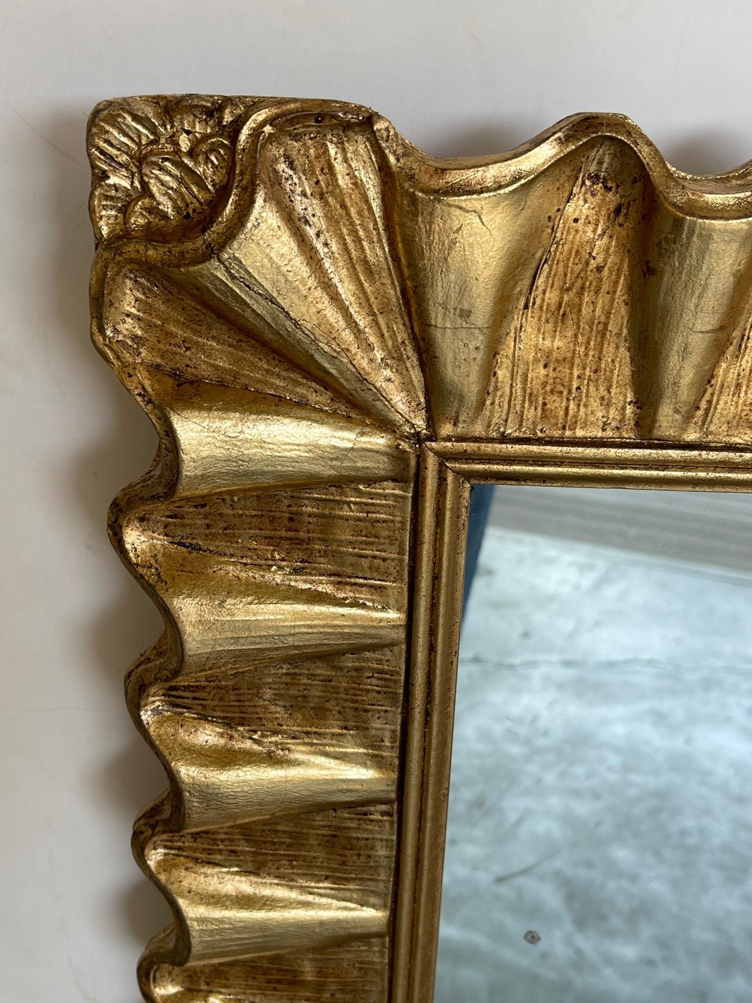 the rectangular mirror within an undulating gilt frame giving the appearance of small folds; can also be hung horizontally