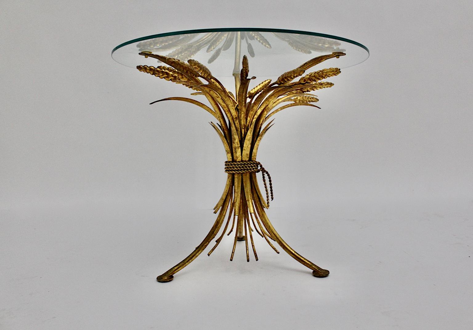 Hollywood regency Style gold vintage coffee table or side table designed and executed France 1970s.
Inspired by nature the designer of the small, amazing, gilded coffee table created a gilded steel base in sheaf of wheat form and a clear round glass