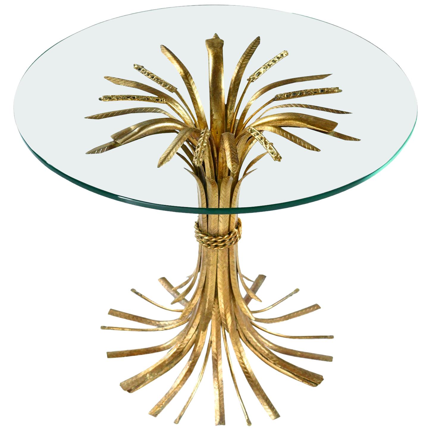 Elegant and luxurious, this Italian Hollywood Regency table glamorizes the humble wheat sheaf. The table is made of sculpted metal with a gold gilt finish and topped with a piece of circular glass. The circle glass top balances on top of the wheat