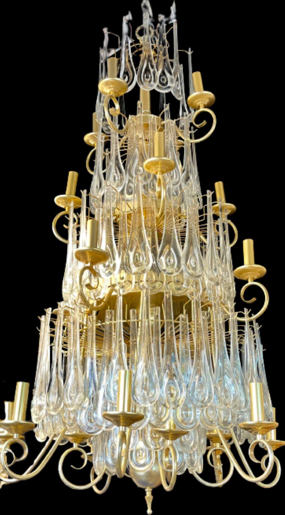 A finely cast gilt bronze tiered chandelier having large and impressive crystals. This one of a kind lighting fixture is simply stunning and certain to spark up conversation. 25 lights in total, having 4 lights on the top, 4 lights on the 2nd tier,