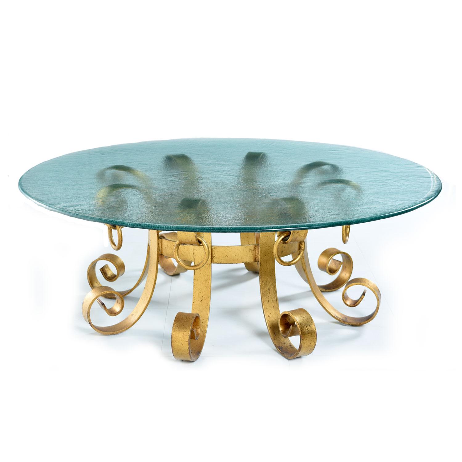 Spectacular vintage Hollywood Regency coffee table with rippled glass top. Heavy, iron metal base gilded with gold and black fleck color paint. Elegant blossoming scroll form with heavy knocker embellishments. Outstanding craftsmanship with