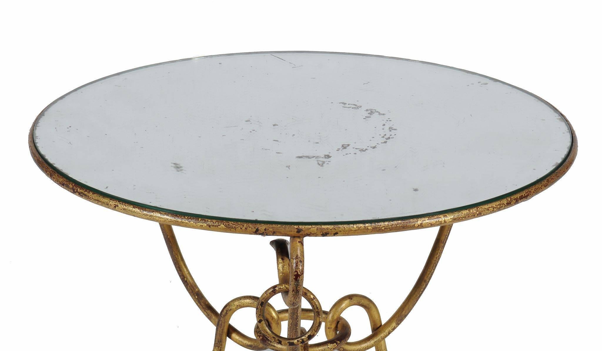 Magnificent Hollywood Regency style round gilt iron coffee or centre table with mirrored top by René Drouet (1899-1993), circular mirrored top with aged mirror spots over gilt iron base on three legs and links, dating to circa