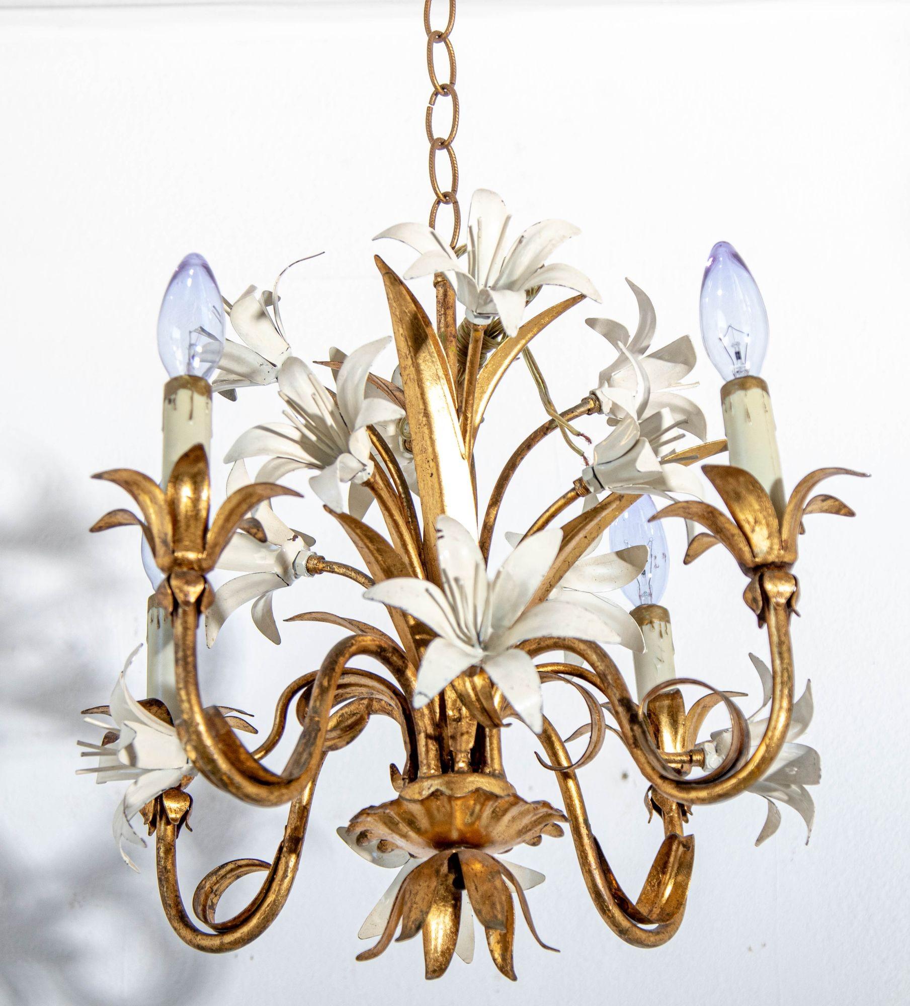 Hollywood Regency Style Gilt Metal Four-Light Chandelier with White Lily Flowers.
This is a vintage Hollywood Regency era gilt tole chandelier with a plethora of ivory lilies.
A beautiful Italian gilt metal four arms chandelier from the 1960s.
This