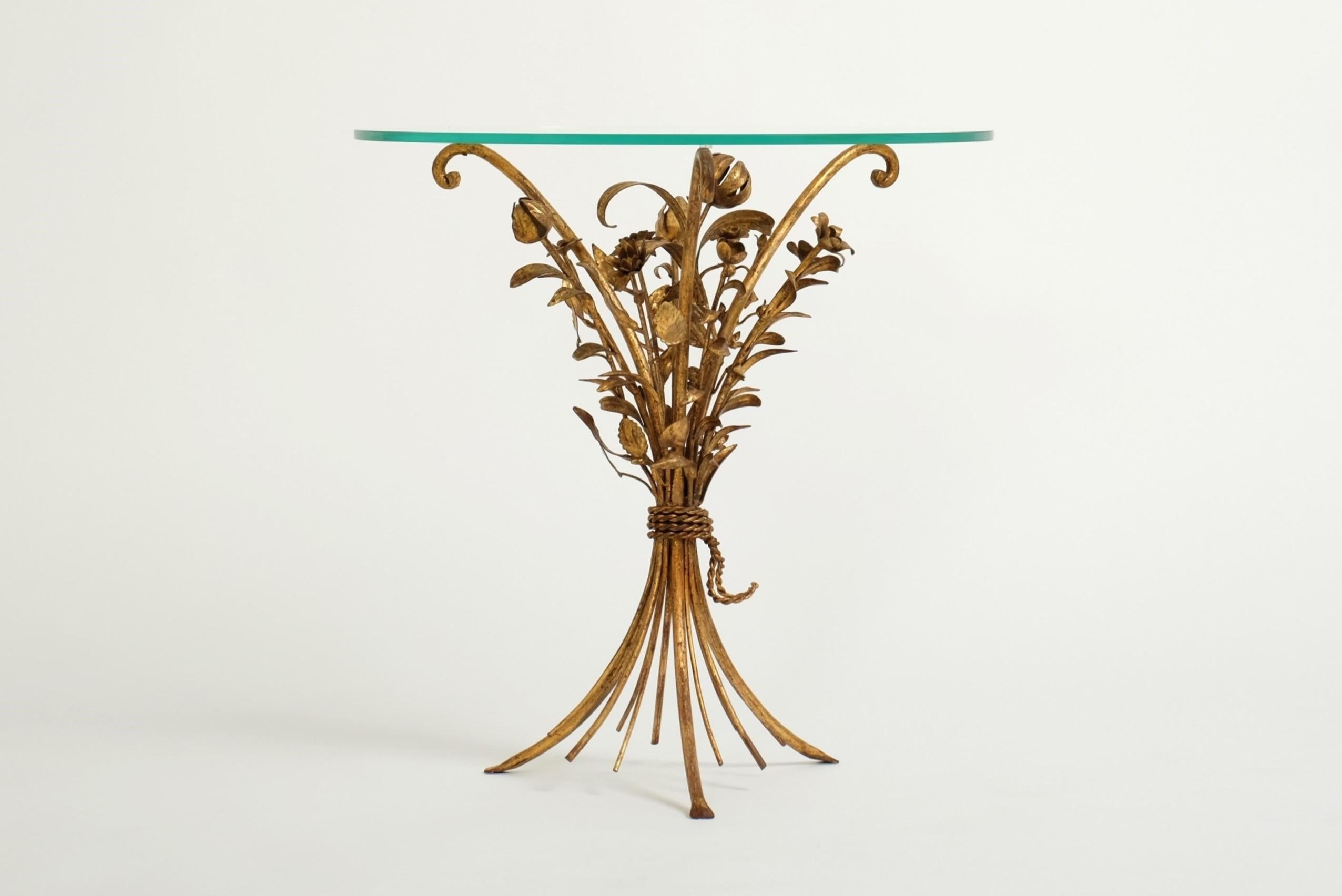Un bellissimo tavolino da caffè/tavolino dorato e floreale degli anni '70. A forma di bouquet di rose, è realizzato a mano in metallo dorato con un piano in vetro rotondo. La struttura del tavolo è in buone condizioni e stabile. La doratura si è