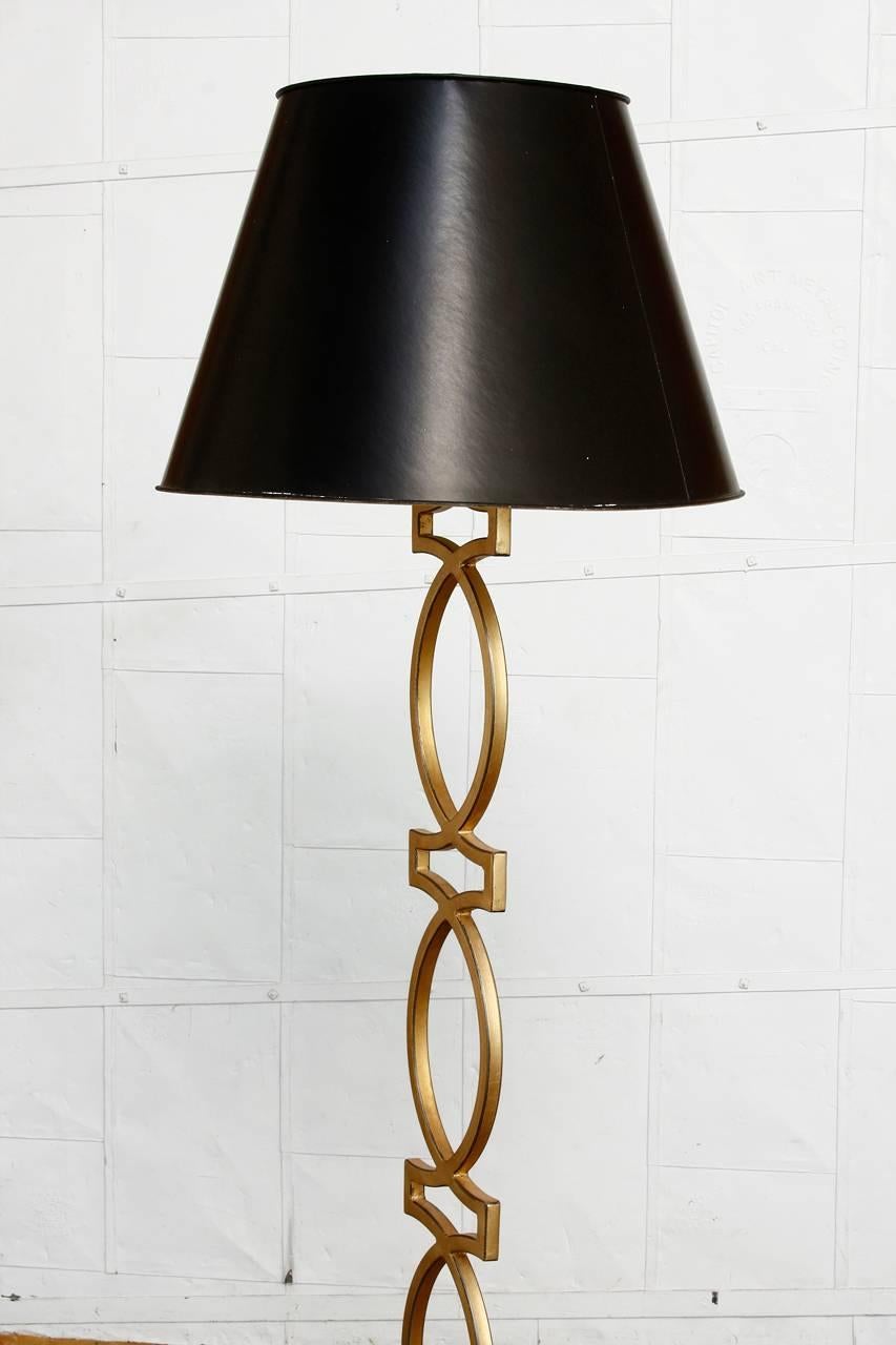 Fabulous gilt metal floor lamp featuring a geometric chain link design made in the Hollywood Regency style. Delicately covered in gold leaf with a distressed finish and double head bronze hardware. The column is supported by a tripod base. Shade