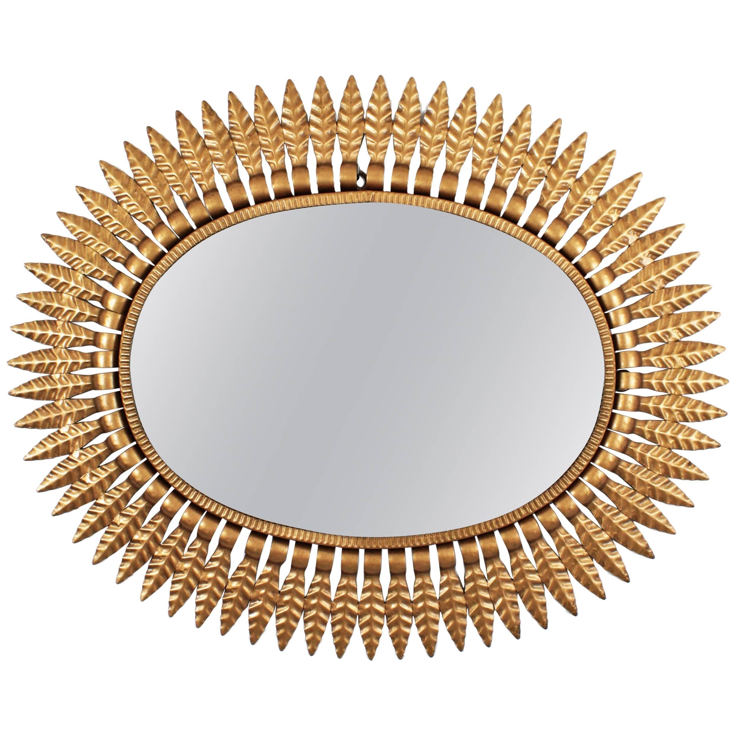 A Hollywood Regency style oval sunburst mirror framed with gilt metal leaves, Spain, 1950s.
This beautiful sunburst mirror manufactured at the mid-20th century period can be placed in two positions and it is interesting to place alone or creating a