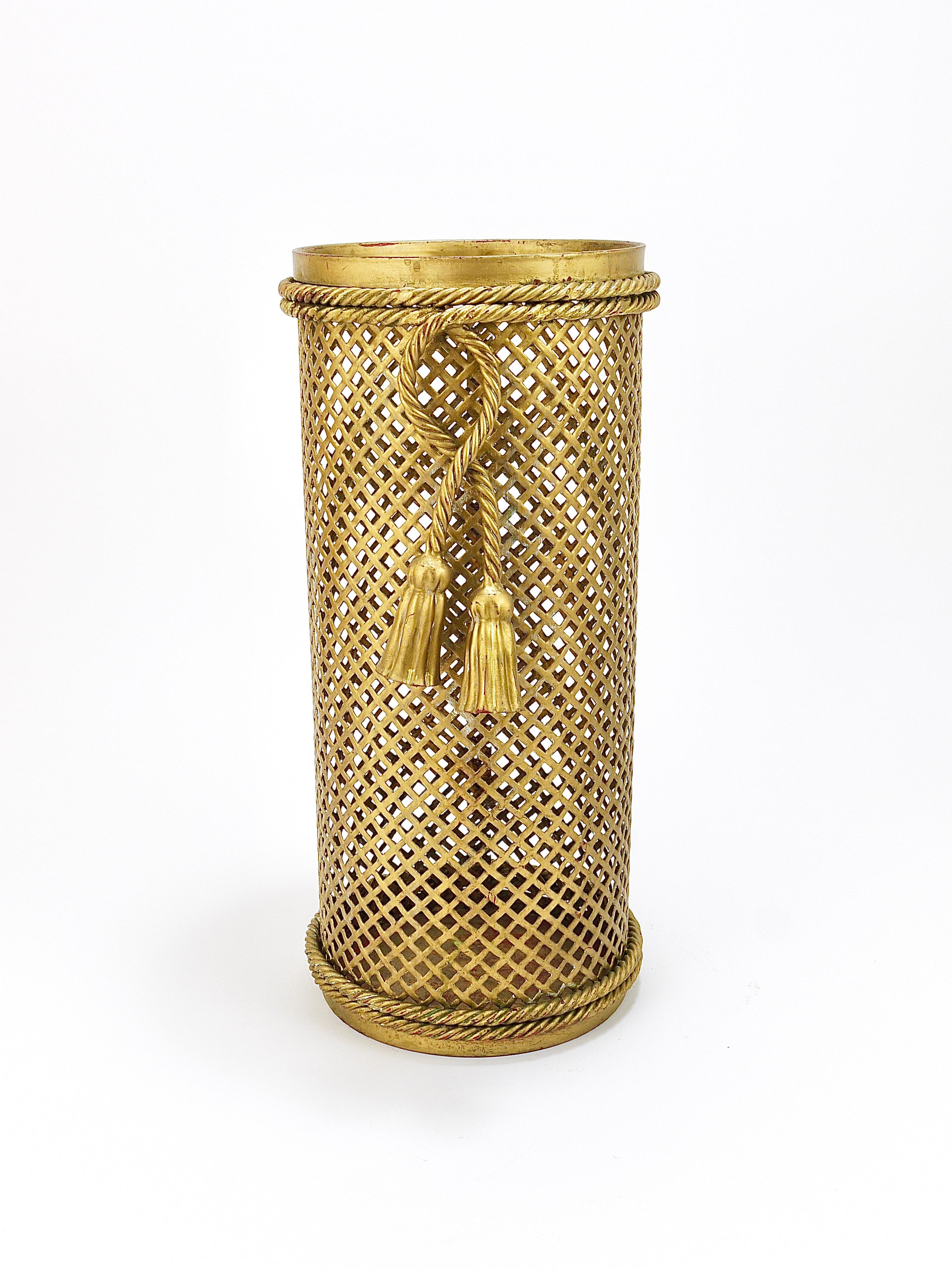 Ein schöner zylindrischer Hollywood Regency Schirmständer aus den 1950er Jahren, hergestellt von Li Puma, Firenze in Italien. Aus gewebtem goldenem Gittermetall, umgeben von einem geknoteten Seil mit zwei Quasten. Kann auch als Papierkorb /
