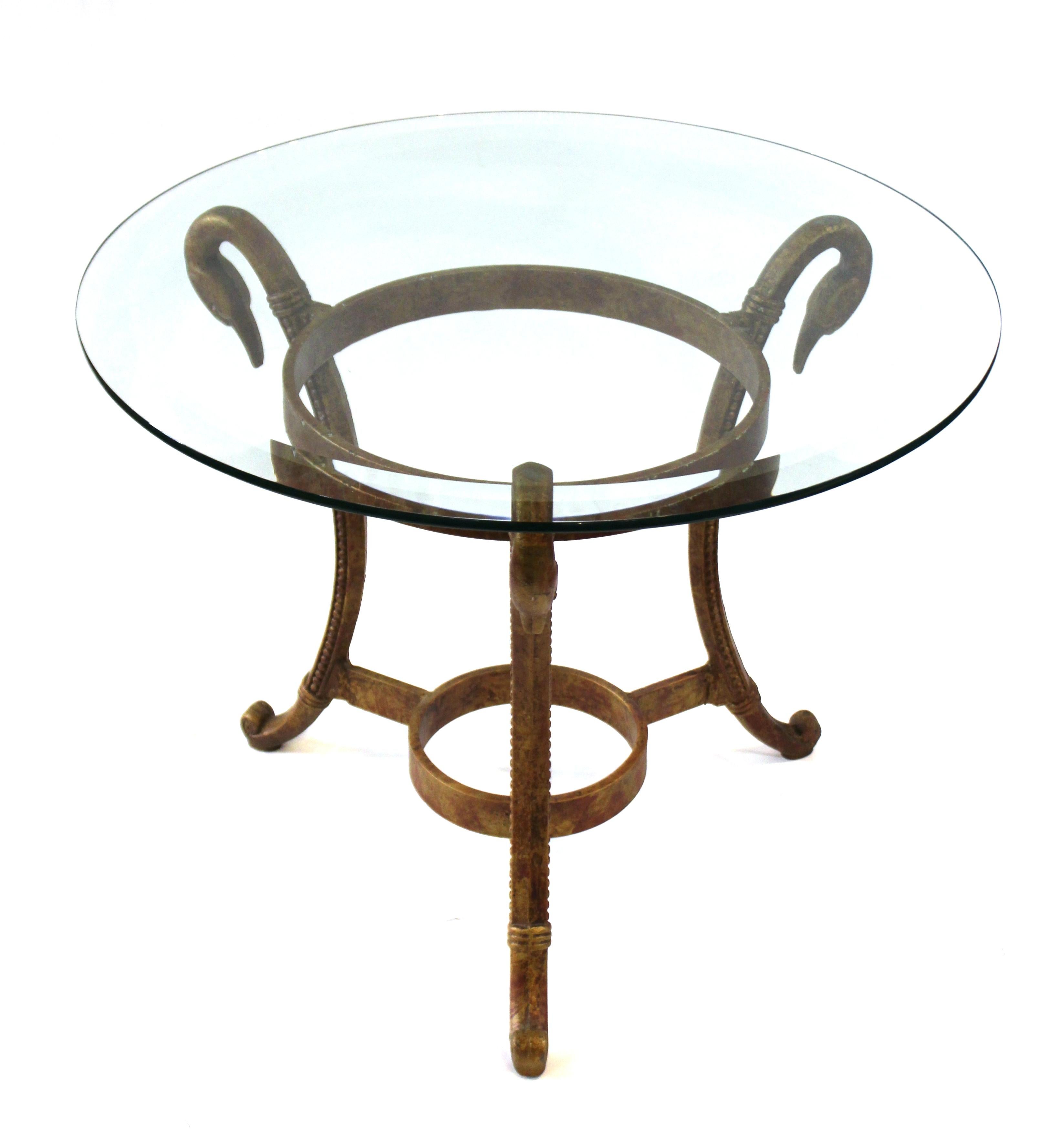 Hollywood Regency side table or center table with circular glass top. The piece has a gilt metal tripod base with decorative swan heads. In great vintage condition with age-appropriate wear and use.