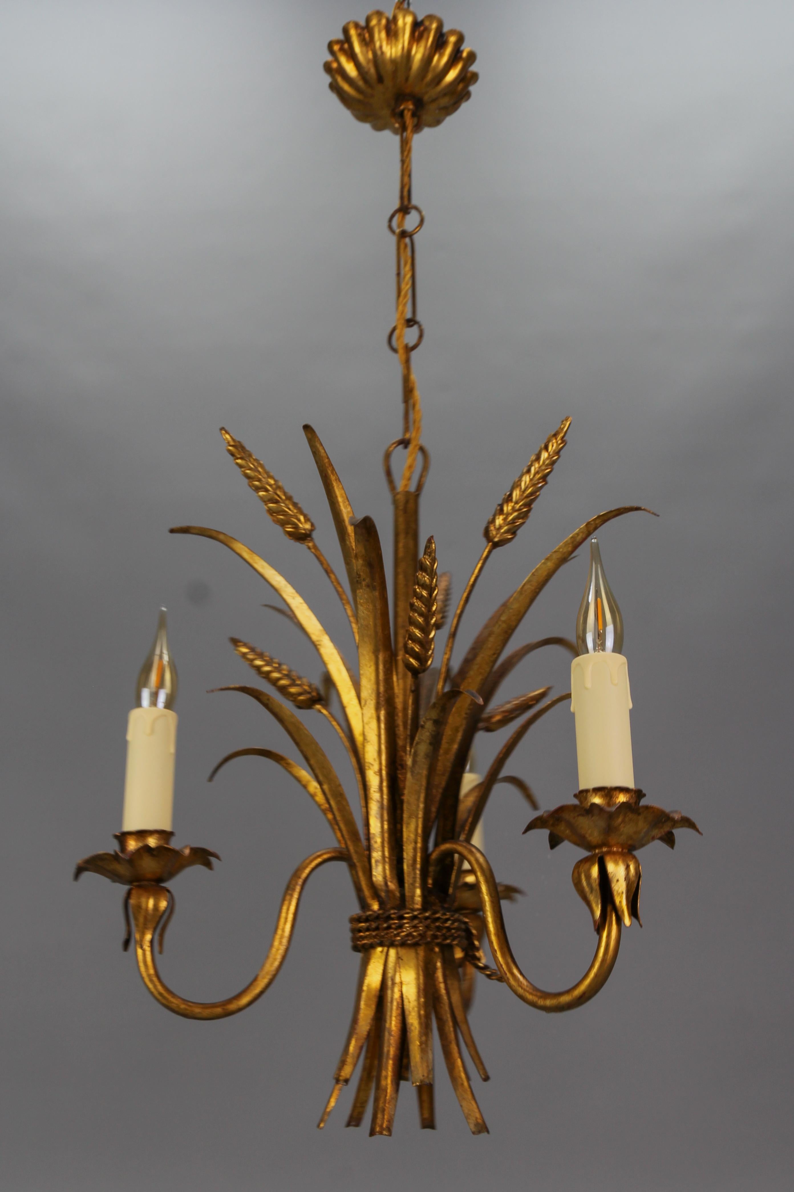 Dreiflammiger vergoldeter Metallkronleuchter im Hollywood-Regency-Stil von Hans Kögl, Deutschland, ca. 1960er Jahre.
Dieser wunderschöne dreiarmige Kronleuchter aus vergoldetem Metall hat die Form einer Weizengarbe - mit Blättern und Ähren, die mit