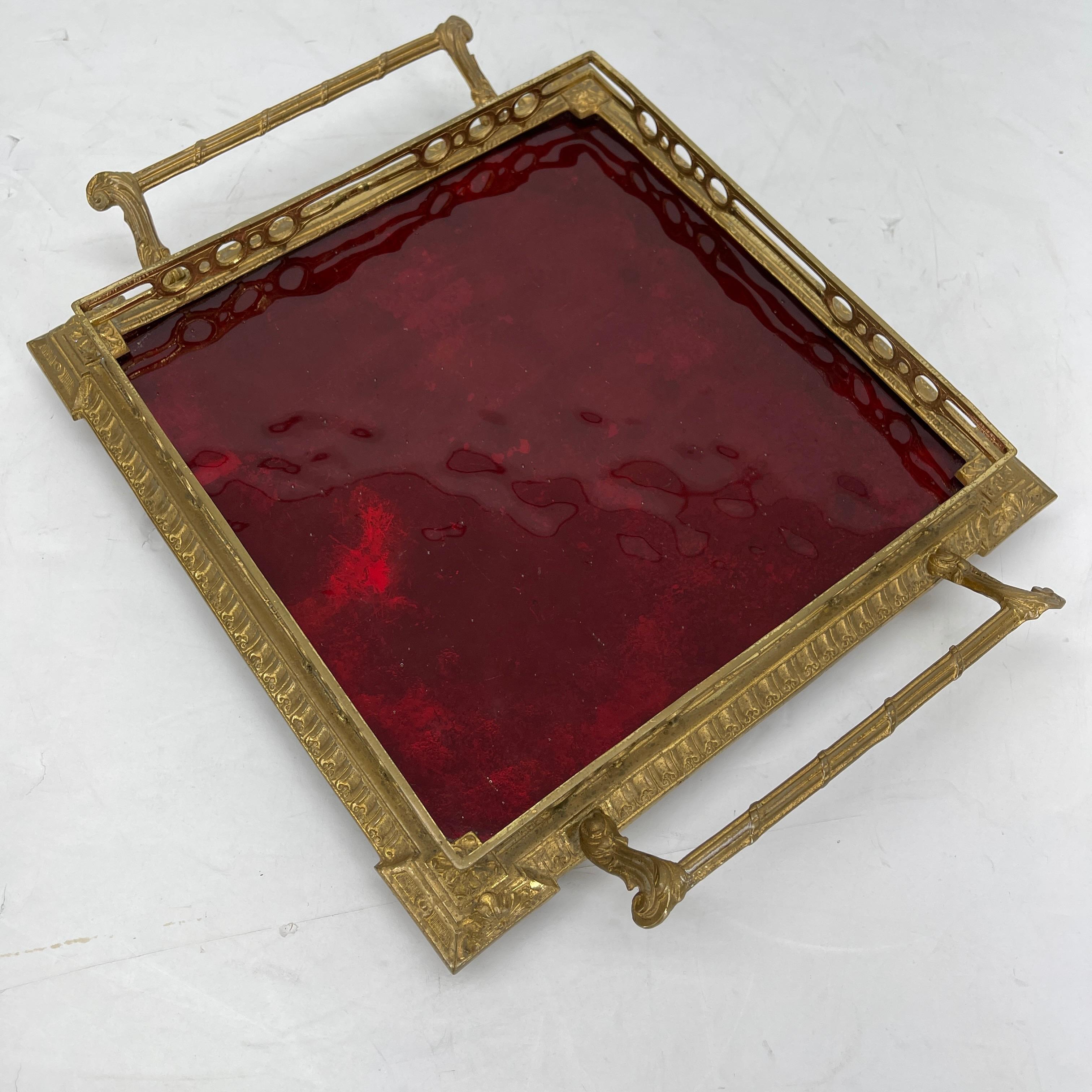 Hollywood Regency gilded vanity tray with red glass insert. This beautiful vanity or serving tray is stunning. It is ornate and has delicate feet. The red glass glows in the light. It is perfect as a vanity tray for displaying bottles of perfume or