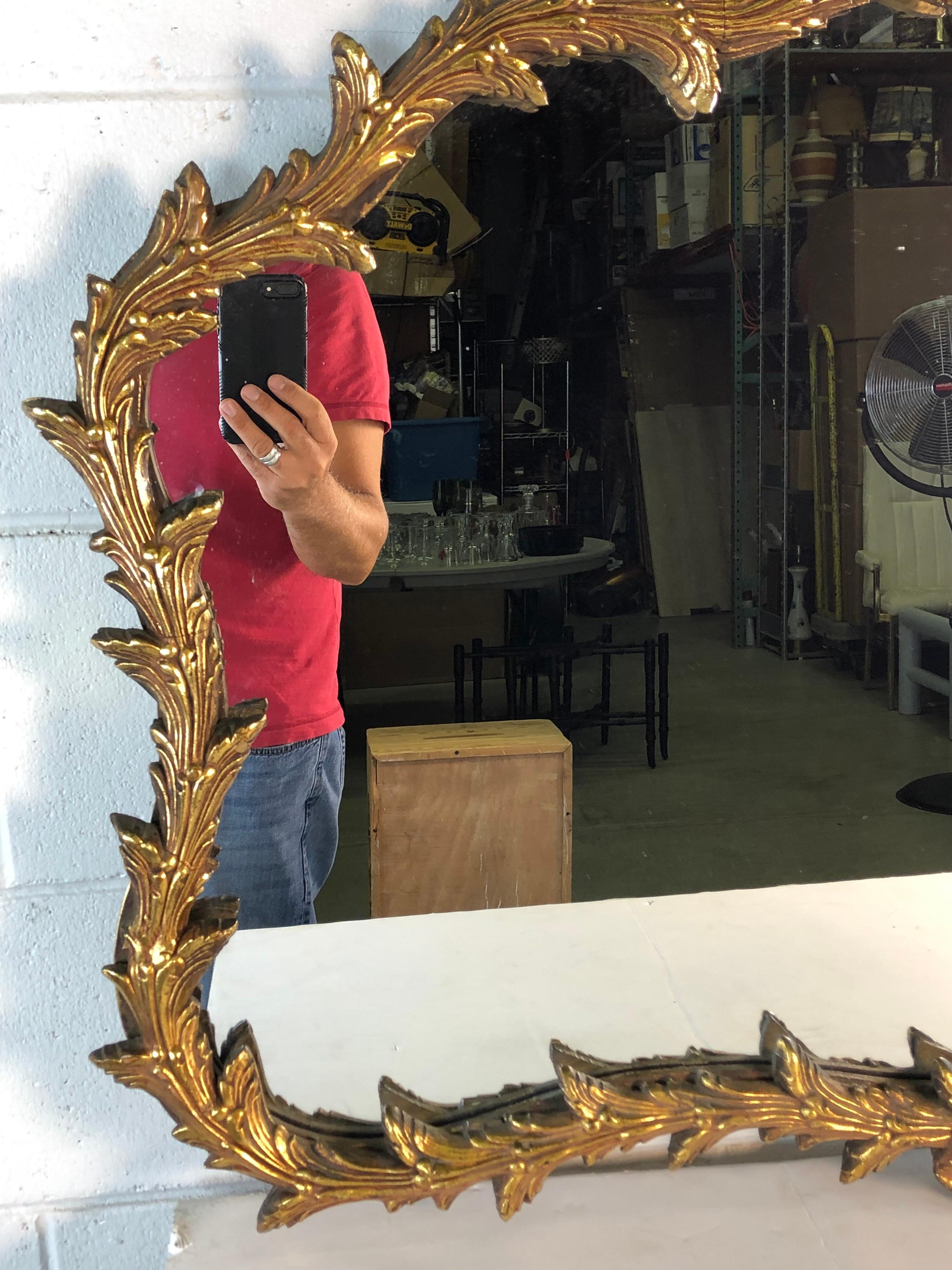 Hollywood Regency giltwood bow and leaf design wall mirror. Mirror is in excellent condition. No hardware. No marks.