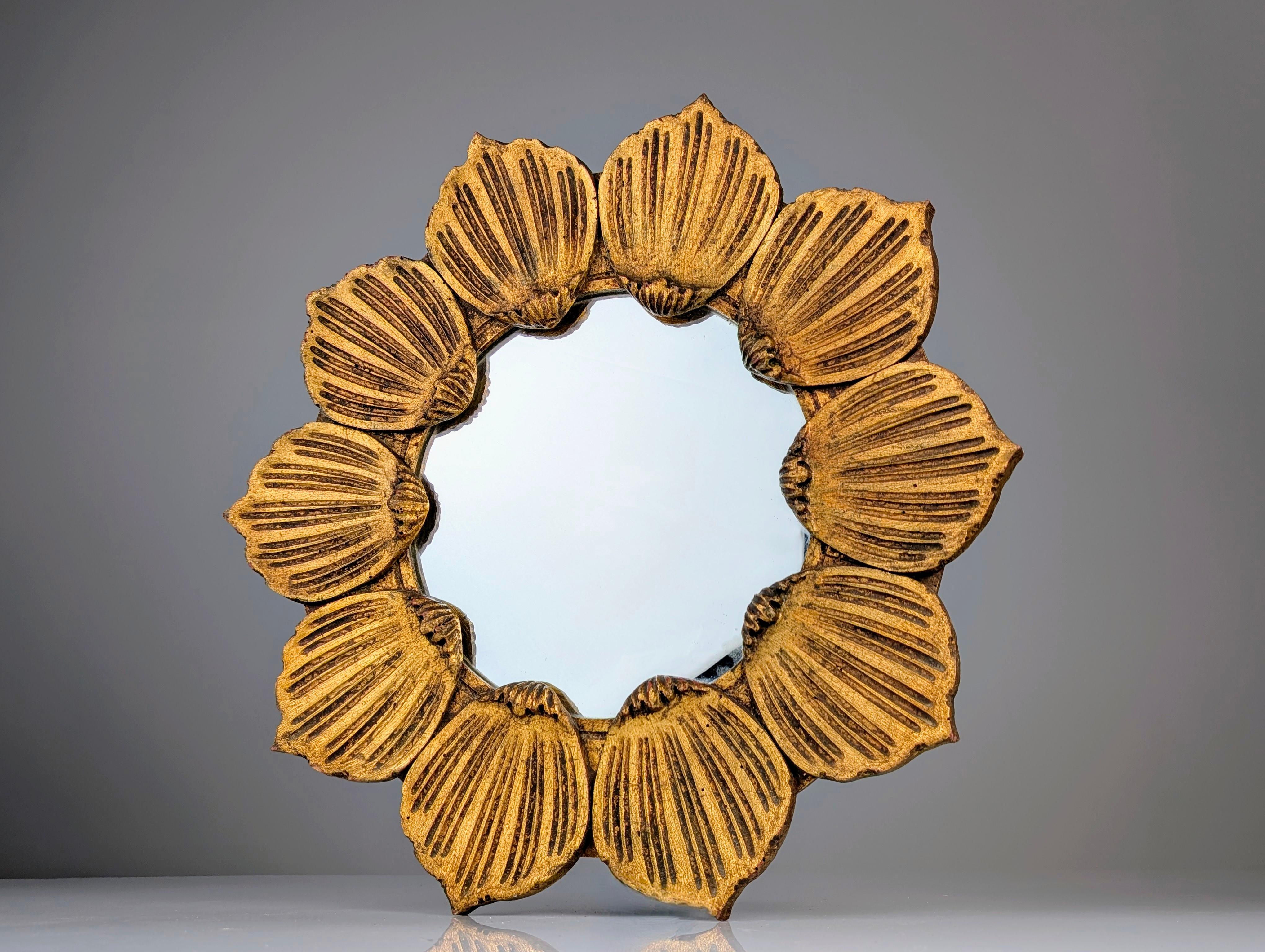 Precioso espejo francés de los años 50, tallado en madera con forma de flor y acabado en pan de oro. Una pieza muy decorativa con pétalos de flores tallados que rodean un vaso circular con todo el sabor del estilo Hollywood Regency.