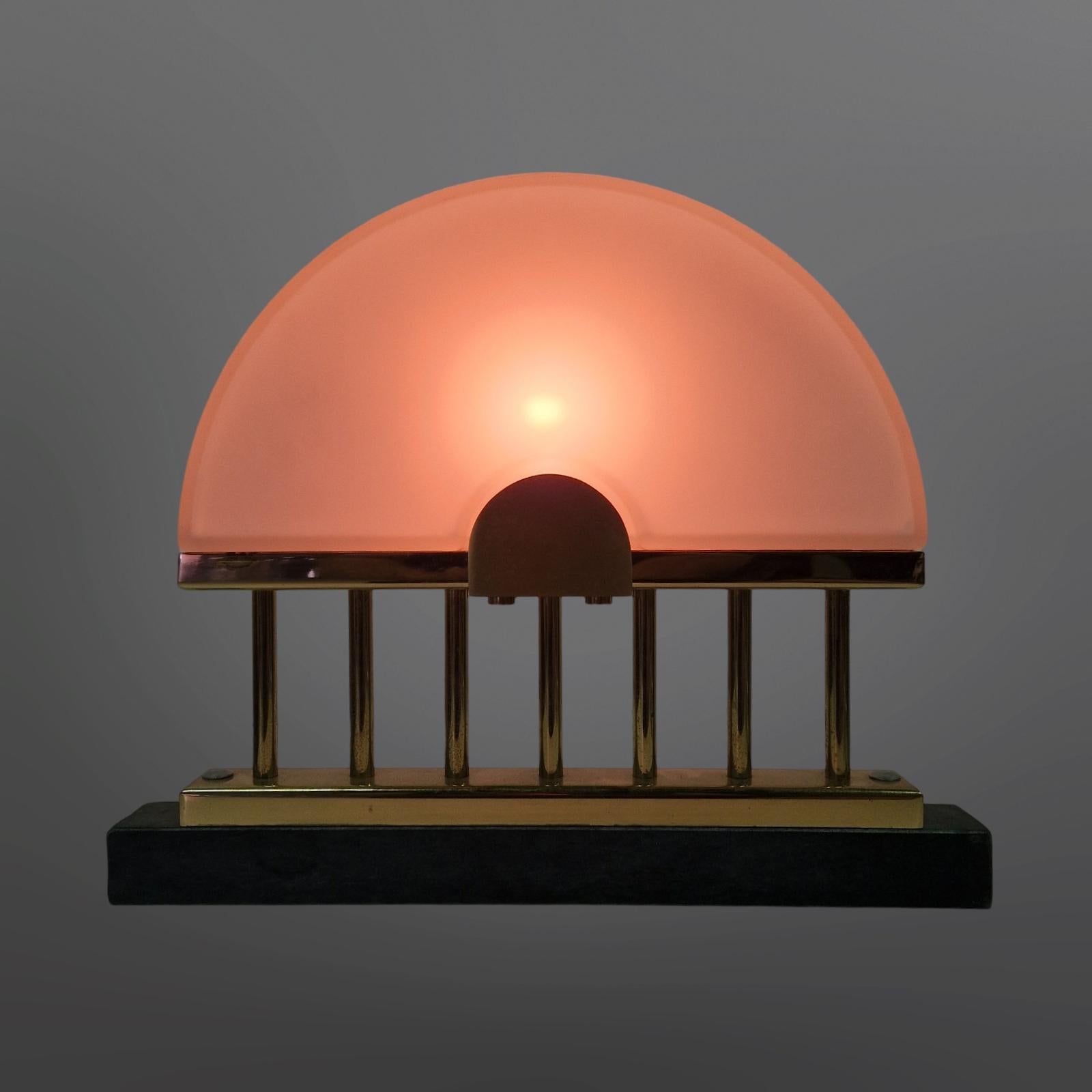 Hollywood regency style lamp. Made from glass, brass and marble. The shade is made from two half circles made from frosted glass. It stands on 7 brass rods. The base is made from green marble. 
