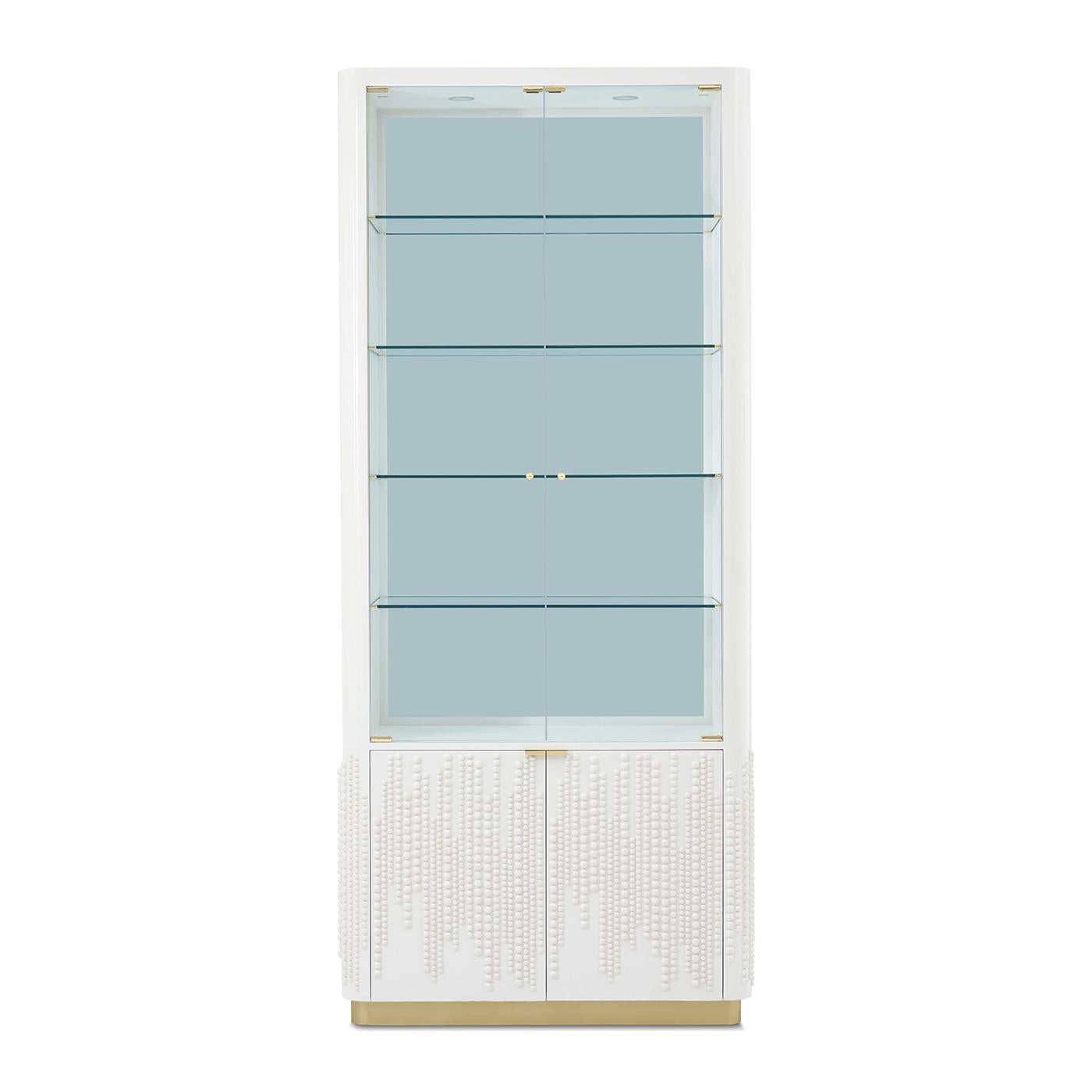 A glamorous fusion of display and storage, wrapped in refined materials and couture-level detail. Framed in crisp white lacquer, this tall cabinet features a gracefully rounded silhouette and gleaming brass accents.

Four glass shelves are set with