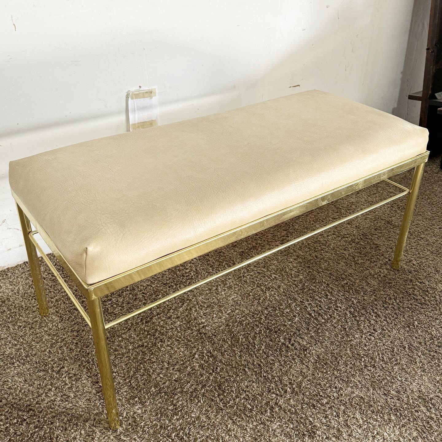 Indulge in the elegance of the Hollywood Regency Gold Bench. With its radiant gold frame and plush beige vinyl faux leather cushion, this bench is a perfect blend of luxury and comfort. It's an ideal statement piece for your living room, bedroom, or