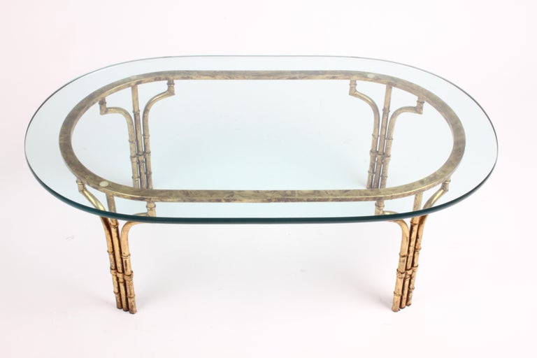 Vintage Italian Hollywood Regency gold gilt faux bamboo base with 3/4 thick oval glass top coffee table. The iron faux bamboo form base has antiqued gold gilt finish, which is in fine condition, minor loss, still has luster. The 3/4 thick oval glass