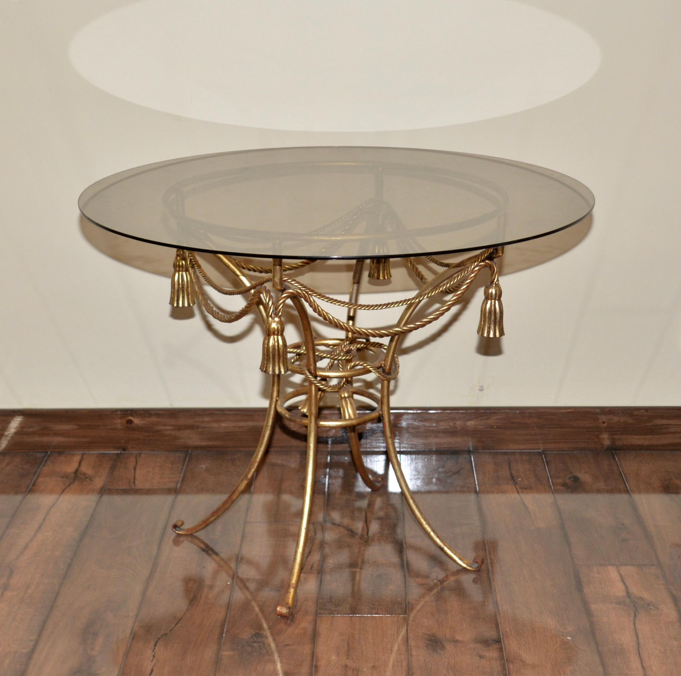 A beautiful vintage gold gilt table with a glass top with lovely intricate detailing on the gold gilt frame and in the style of Hans Kögl. A striking example of the Hollywood Regency style.