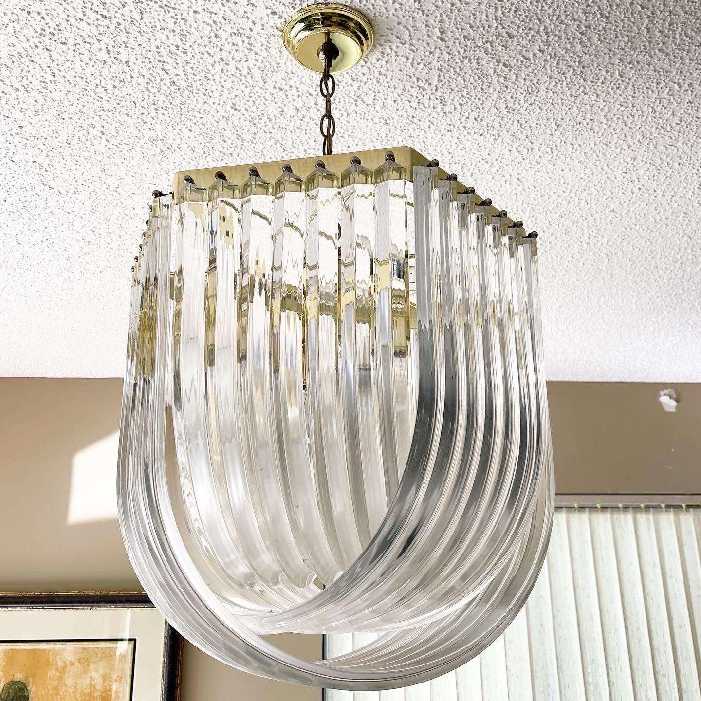Exceptional extra large vintage Hollywood regency gold lucite ribbon loop chandelier. In the style of Carlo Nason this curved clear lucite triedri prism chandelier is jaw dropping.