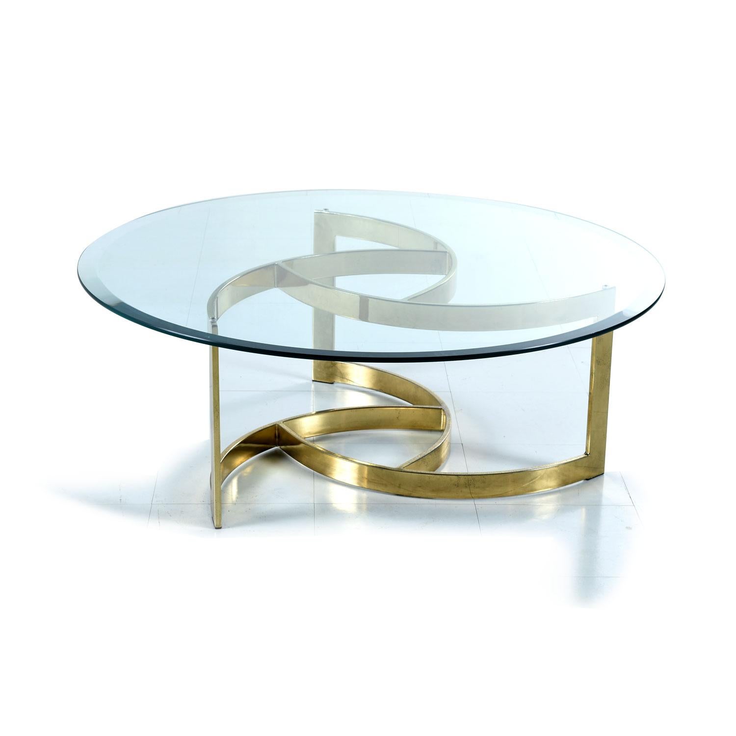 This glamorous gold colored coffee table features a beveled circular glass top. The circle top is complimented by the graceful spiral shaped brass base. Light glimmers through the crystalline glass and glittering gold metallic finish. Your coffee