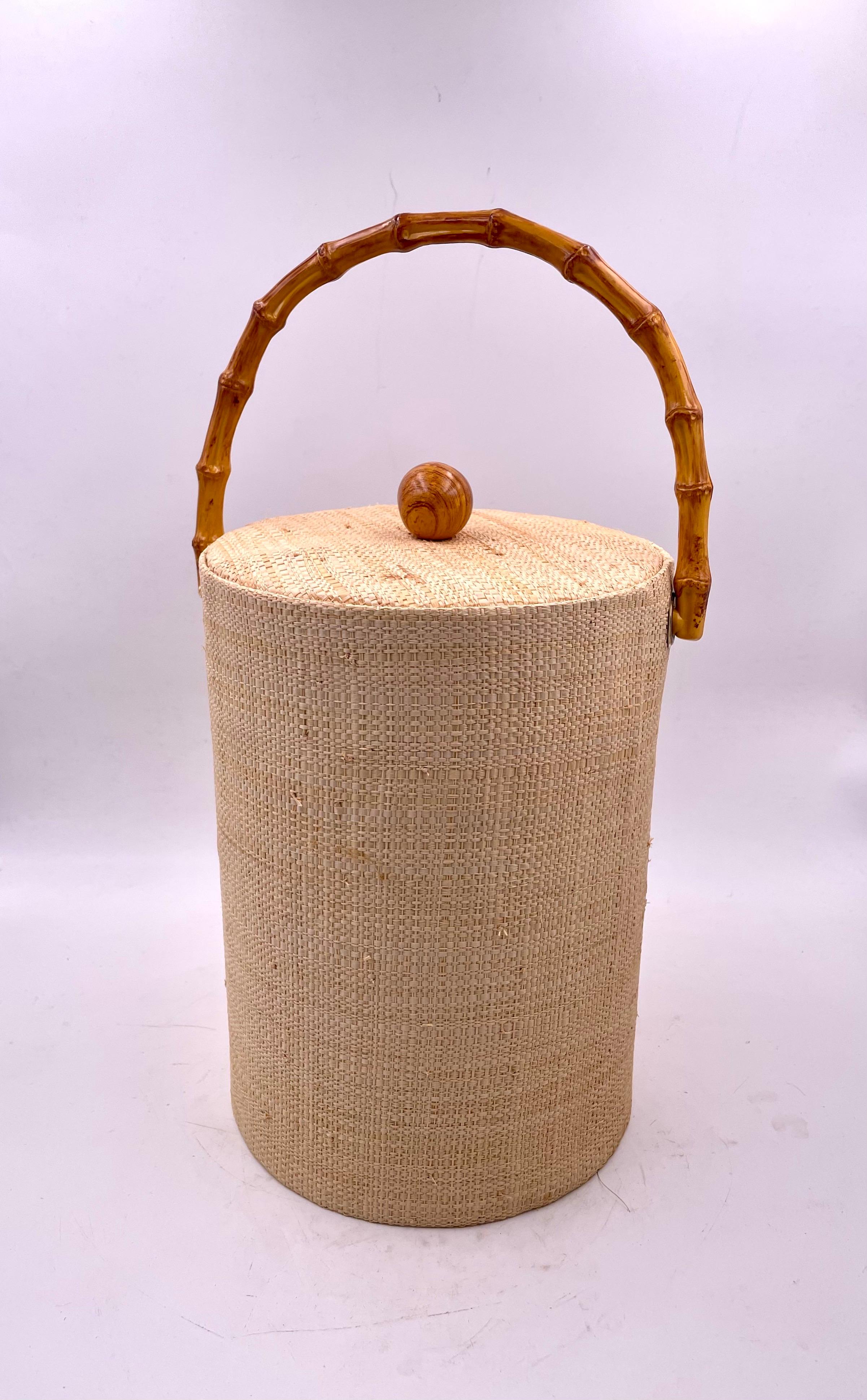 Beautiful grasscloth wrapped ice bucket and tongues, circa 1970's with faux bamboo finish handle great condition.