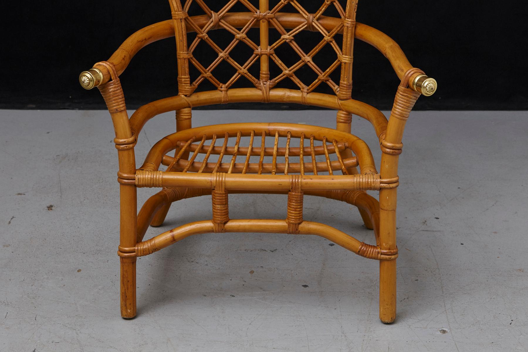 Lovely Hollywood Regency rattan armchair with a high back fan style and brass elements at the end of the armrests, circa 1960s.
The chair is in good solid condition, one of the rattan sticks in the seat area has a clean break, which has been