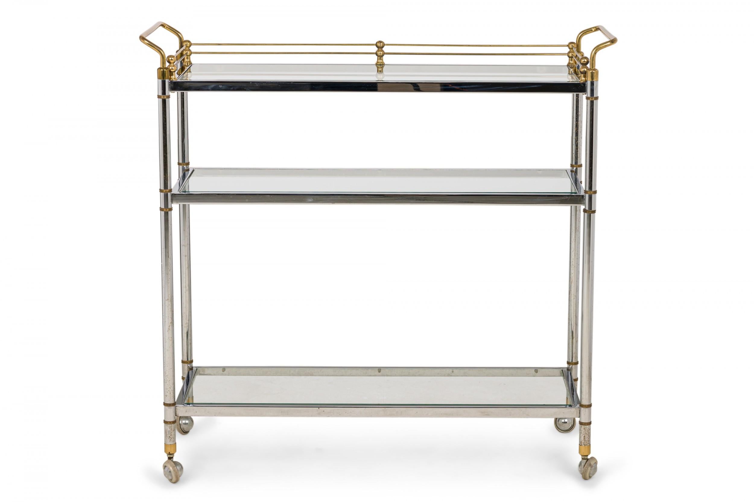 Hollywood Regency High Style Mid-Century 3-tier serving trolley with a rectangular chrome and brass frame with clear glass shelves, resting on four casters.
 
