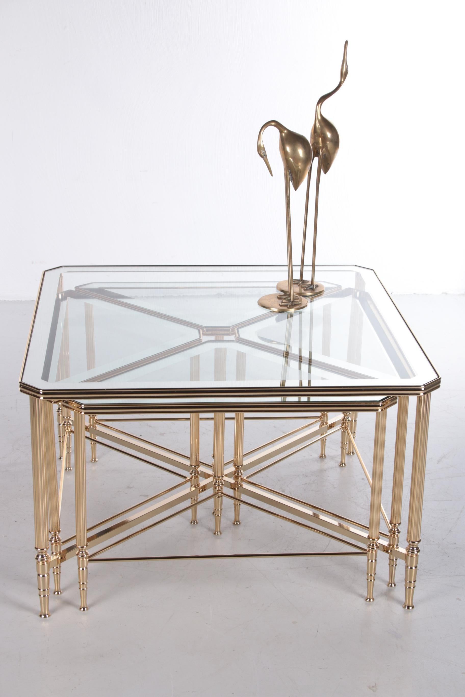 Beautiful classic Hollywood Regency coffee/cocktail table, with four triangular side tables nesting under the square master table.

The glass tops have a silver mirror edge, and the glass is original and in good condition. The gold-colored frame is