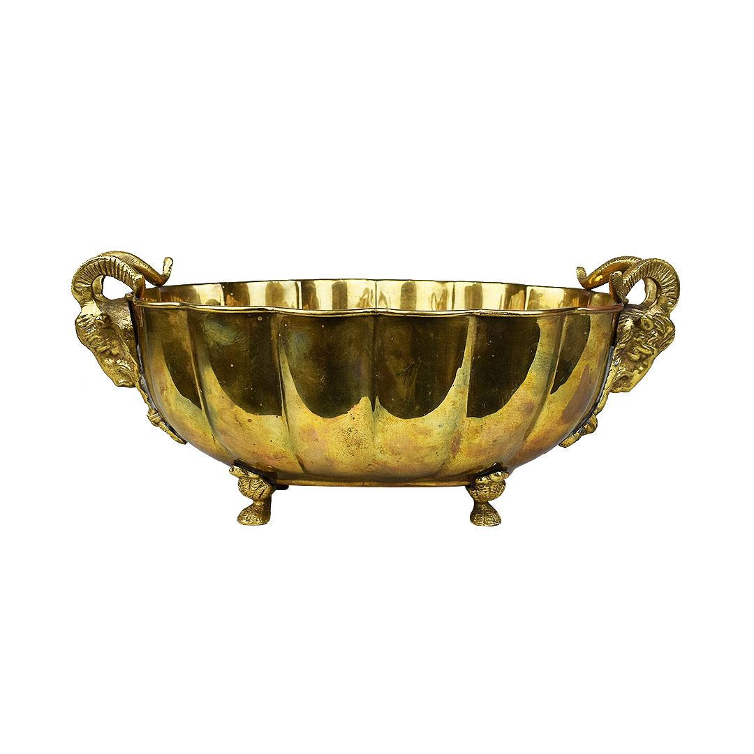 Figurative brass head bowl with hoof feet. A lovely Hollywood Regency style bowl which features scalloped edges and large ram heads at each side. This piece sits upon four hoofs and is perfect for use as a planter, decorative dish in a living room,