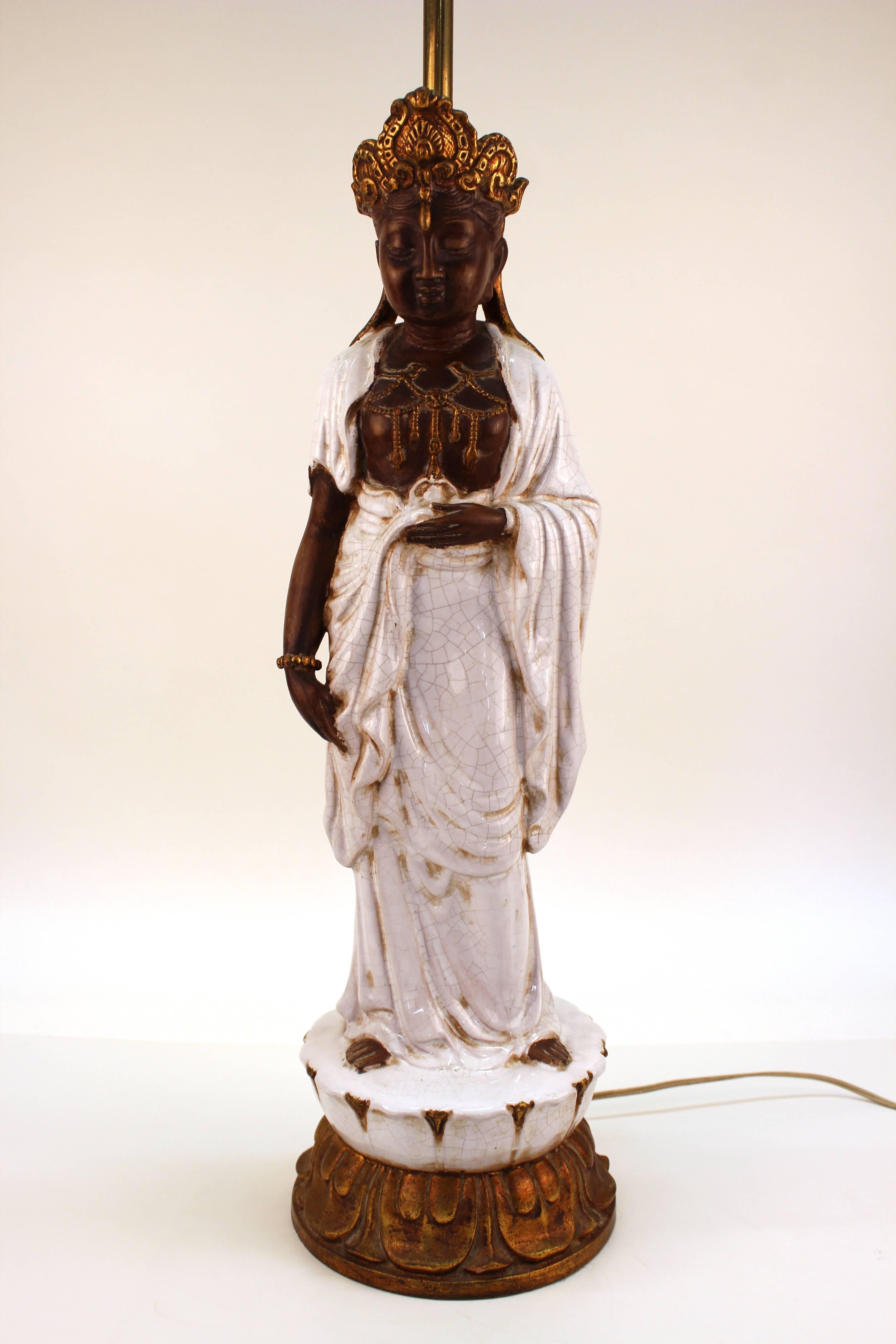 A Hollywood Regency table lamp made in glazed ceramic and depicting a standing Buddha. The piece was made in Italy and is marked on the inside border [VZ] [Italy]. In good vintage condition with some wear to the finish.