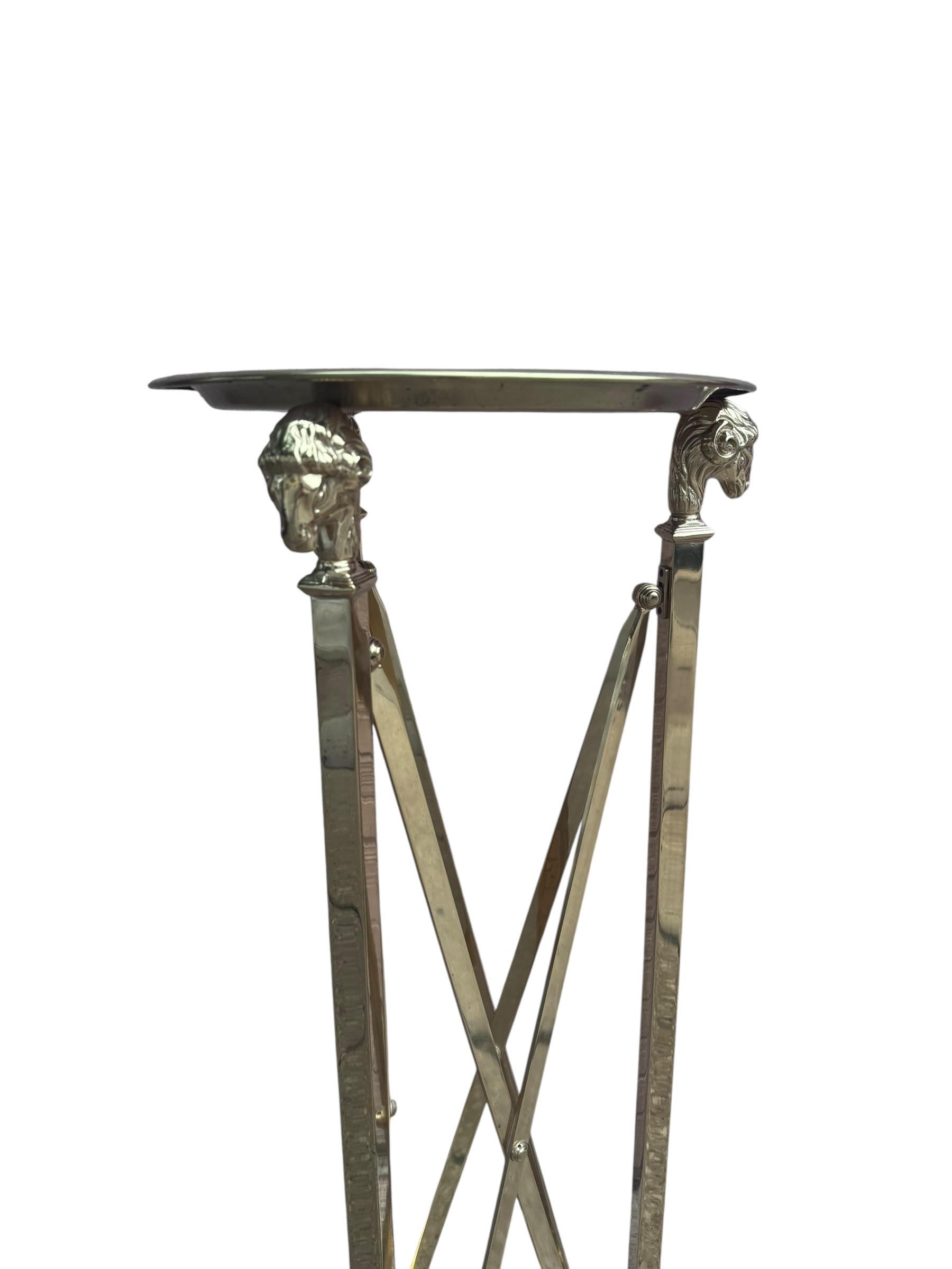 Tavolo con vassoio a piedistallo in ottone Madison Jansen, Hollywood Regency italiano 

Favoloso piedistallo alto in ottone della Maison Jansen con testa di montone e vassoio rimovibile. Base a tre angoli, in ottone, con 3 gambe con barelle a x tra
