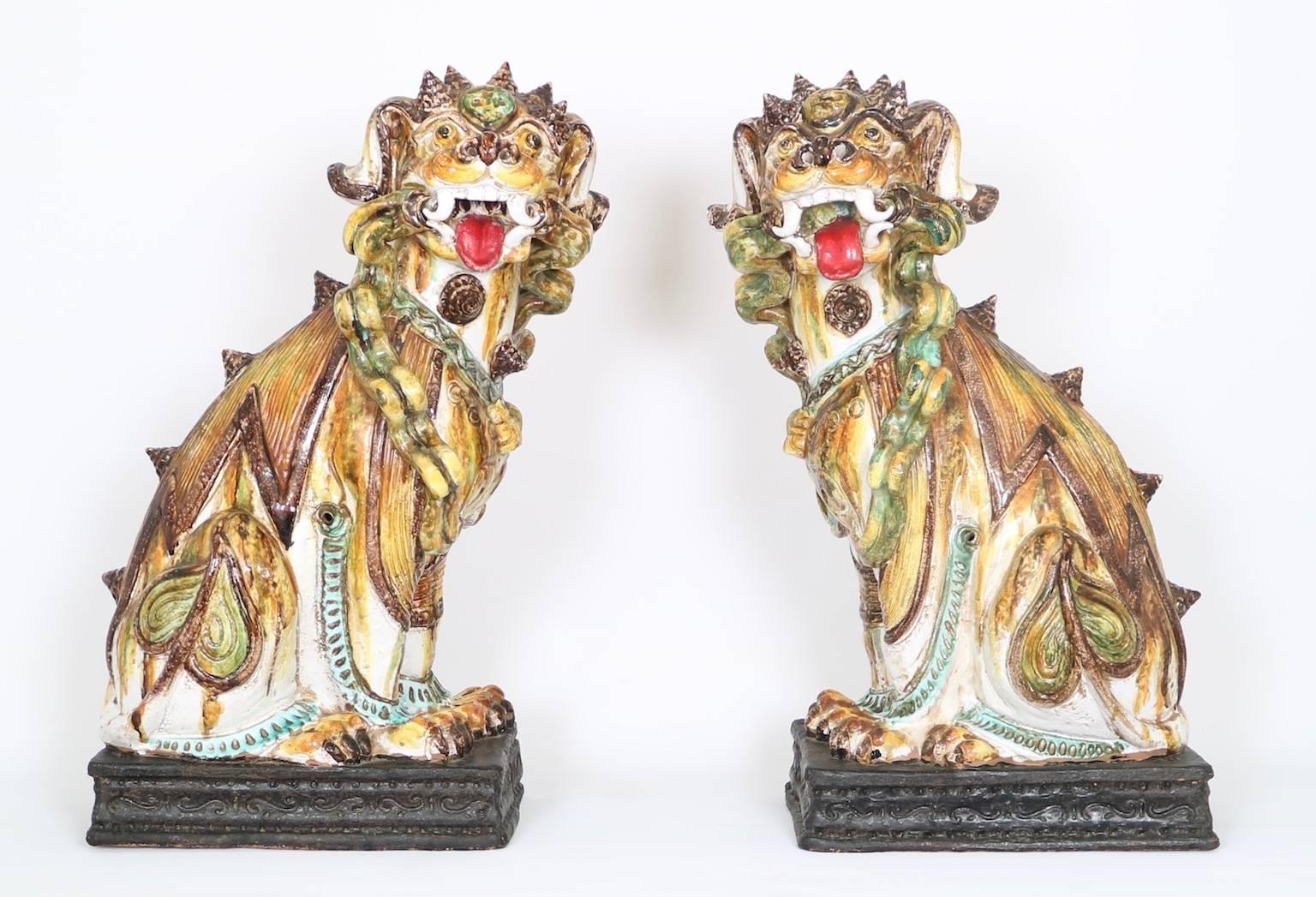 A pair of large terracotta Majolica foo dogs, produced in Italy during the Hollywood Regency era circa 1950s. The pair has multicolored glazes and is an excellent Mid-Century Modern era Italian interpretation of the Chinese models. In excellent