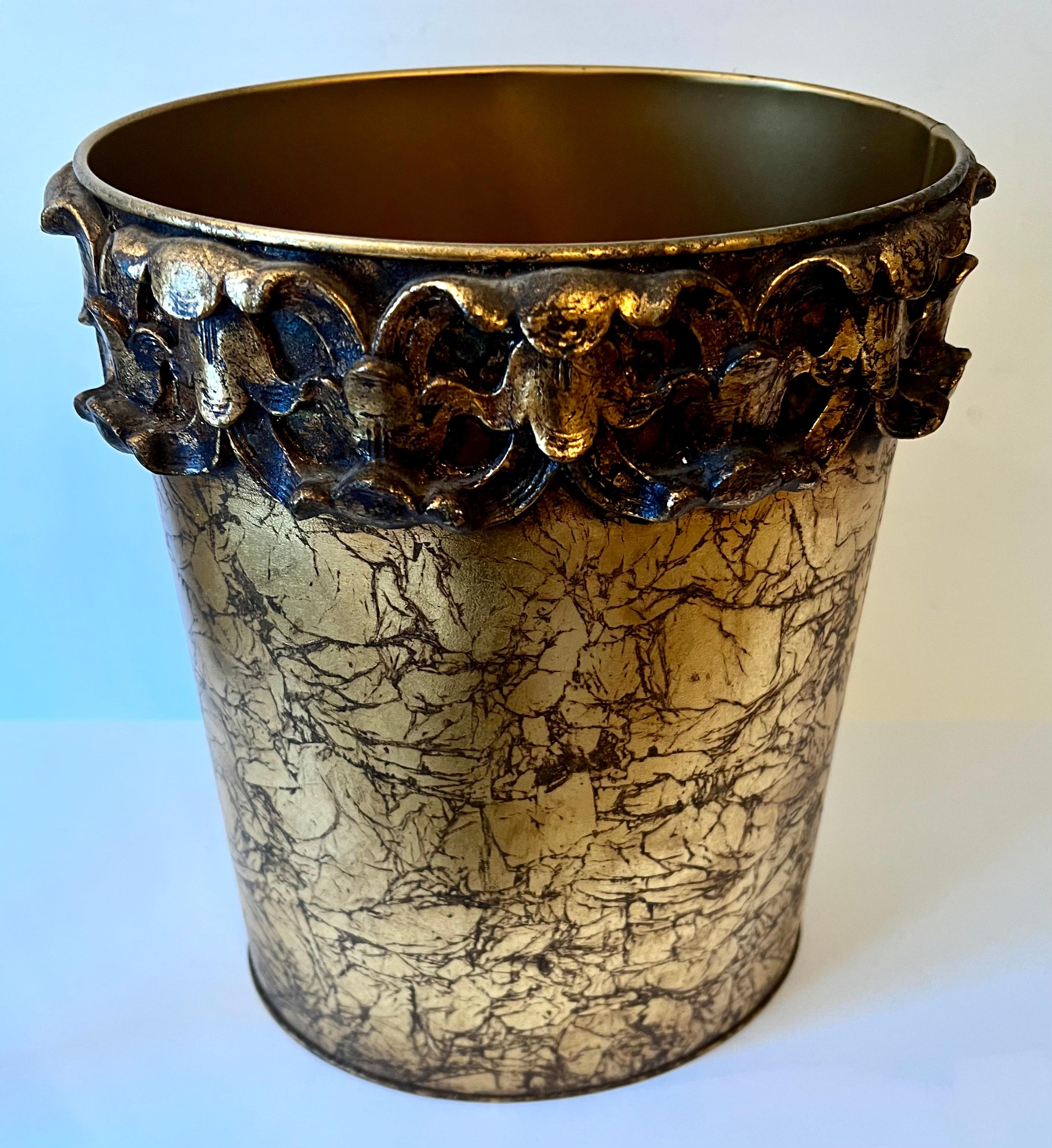 A Oval gold metal waste bin or can. The piece is very mid century, Hollywood regency. a wonderful addition to the guest room, bathroom or office. The gold is variegated and has a floral style relief around the top as a band... very nice.