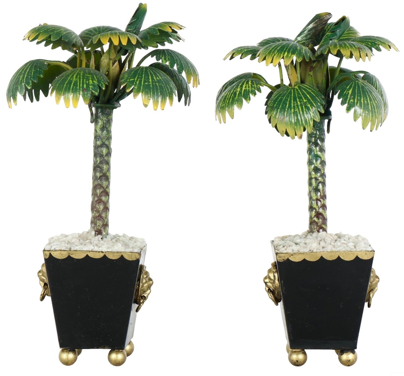 Si tratta di una coppia di palme italiane Hollywood Regency Tole, inserite in vasi di ghiaia finta. I vasi hanno accenti dorati che includono piccole teste di leone. Risalgono alla metà del XX secolo e presentano una certa usura dovuta all'età.