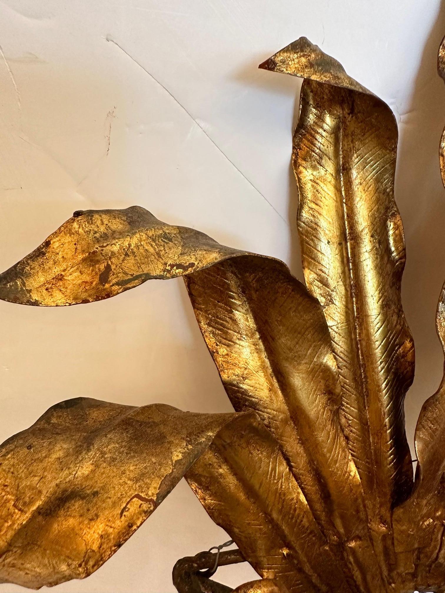 Paire d'appliques vintage glamour en fer doré et tole à motif de palmier avec des prises simples et des feuilles élégamment évasées tombant en cascade d'un vase en tressage de panier.