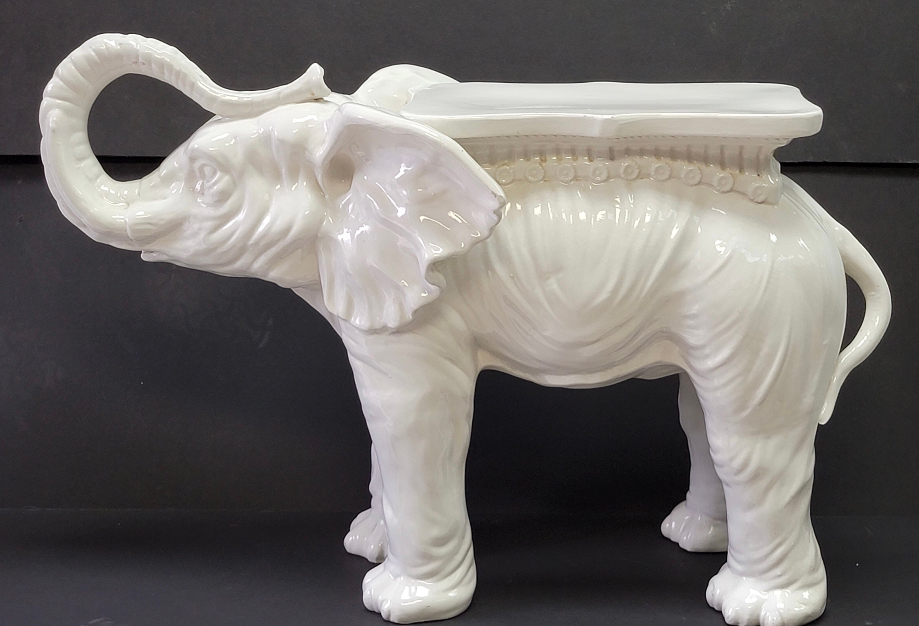This is a mid-century Hollywood Regency Eta elephant form garden seat with blanc de chine styling. It is in very good condition and is signed. The size and detail make this a unique piece.