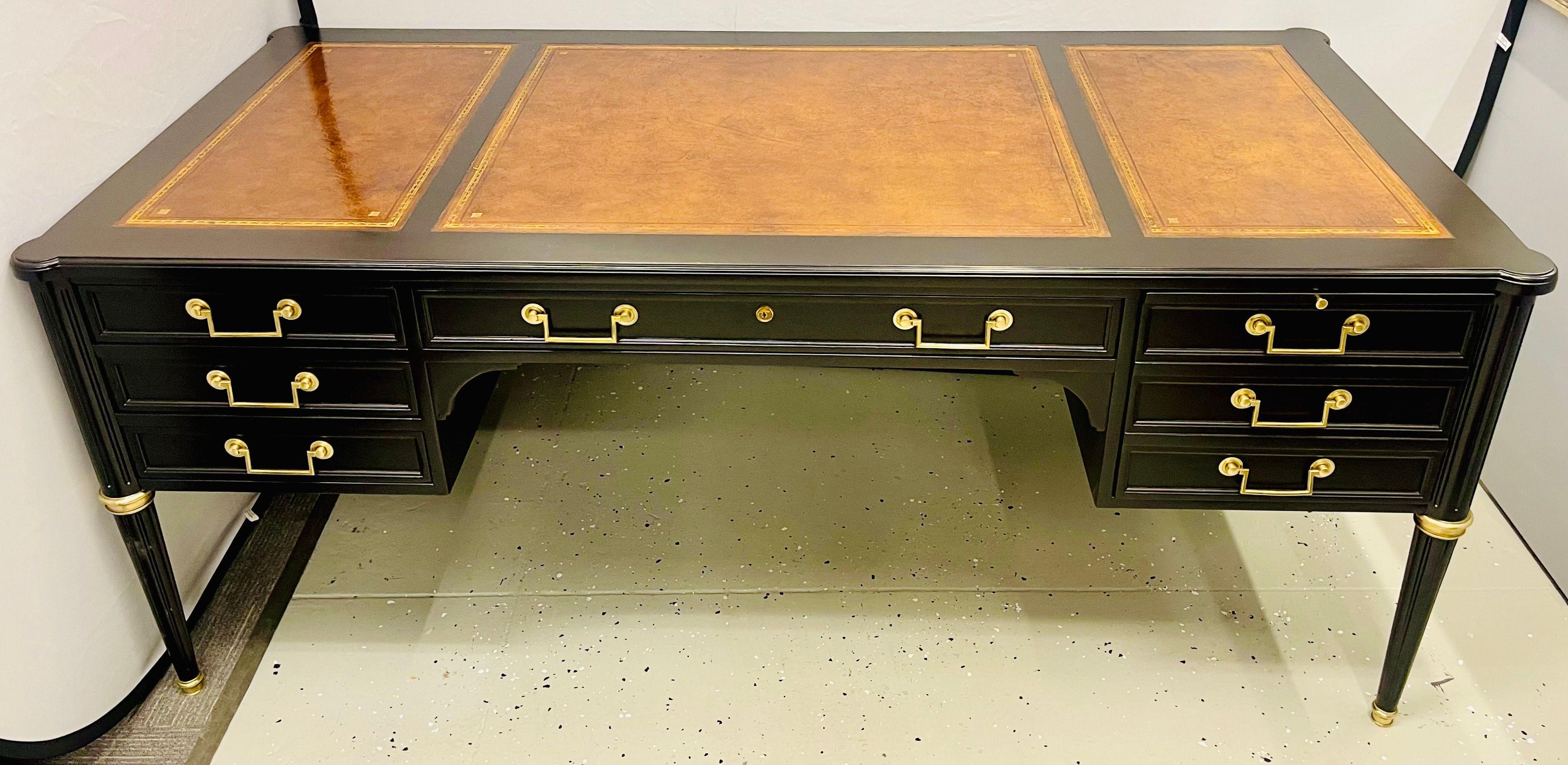 Hollywood Regency Style Desk in the manner or Maison Jansen. A large and impressive ebony partner desk with a nicely worn warm brown Gilt tooled leather top. This Louis XVI Fashion Desk or Writing Table is simply stunning. The sleek tapering legs