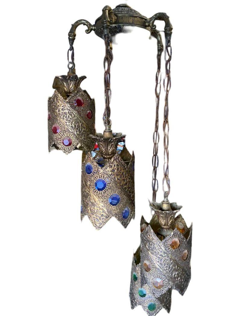 Vintage Hollywood Regency Jewell Filigree Brass Morrocan-inspired 5-light Hanging Ceiling Light Fixture. Il lampadario presenta un punto centrale con cinque lanterne pendenti, ognuna con un Jewell di colore diverso.