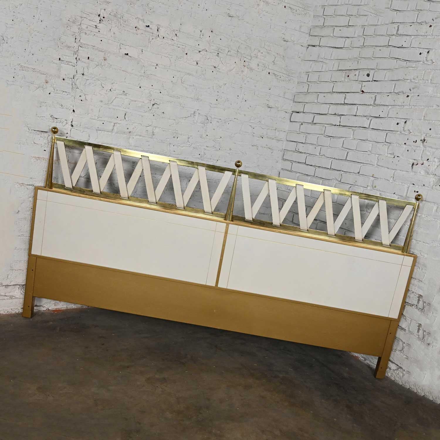 Stunning vintage Hollywood Regency Art Deco king sized headboard by Renzo Rutili for Johnson Furniture. Comprised of white leather front panels with gilded trim and gold painted below, brass tapered conical post accents and a white leather strap