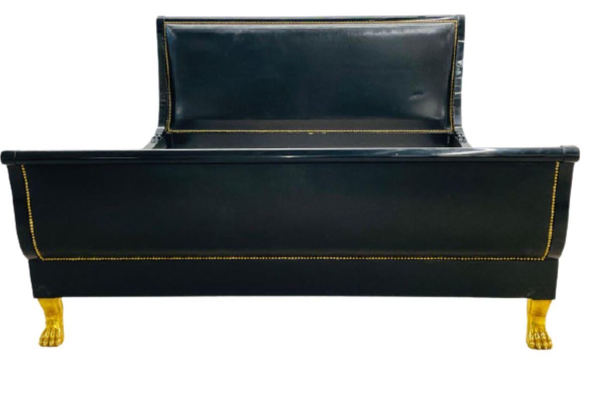 Hollywood Regency King Sized Ebony Bedframe. A Maison Jansen attributed fine custom quality one of a kind bedframe. The frame of ebony lacquered wood with gilt gold wonderfully detailed feet. The whole having a full black leather tacked finished, on