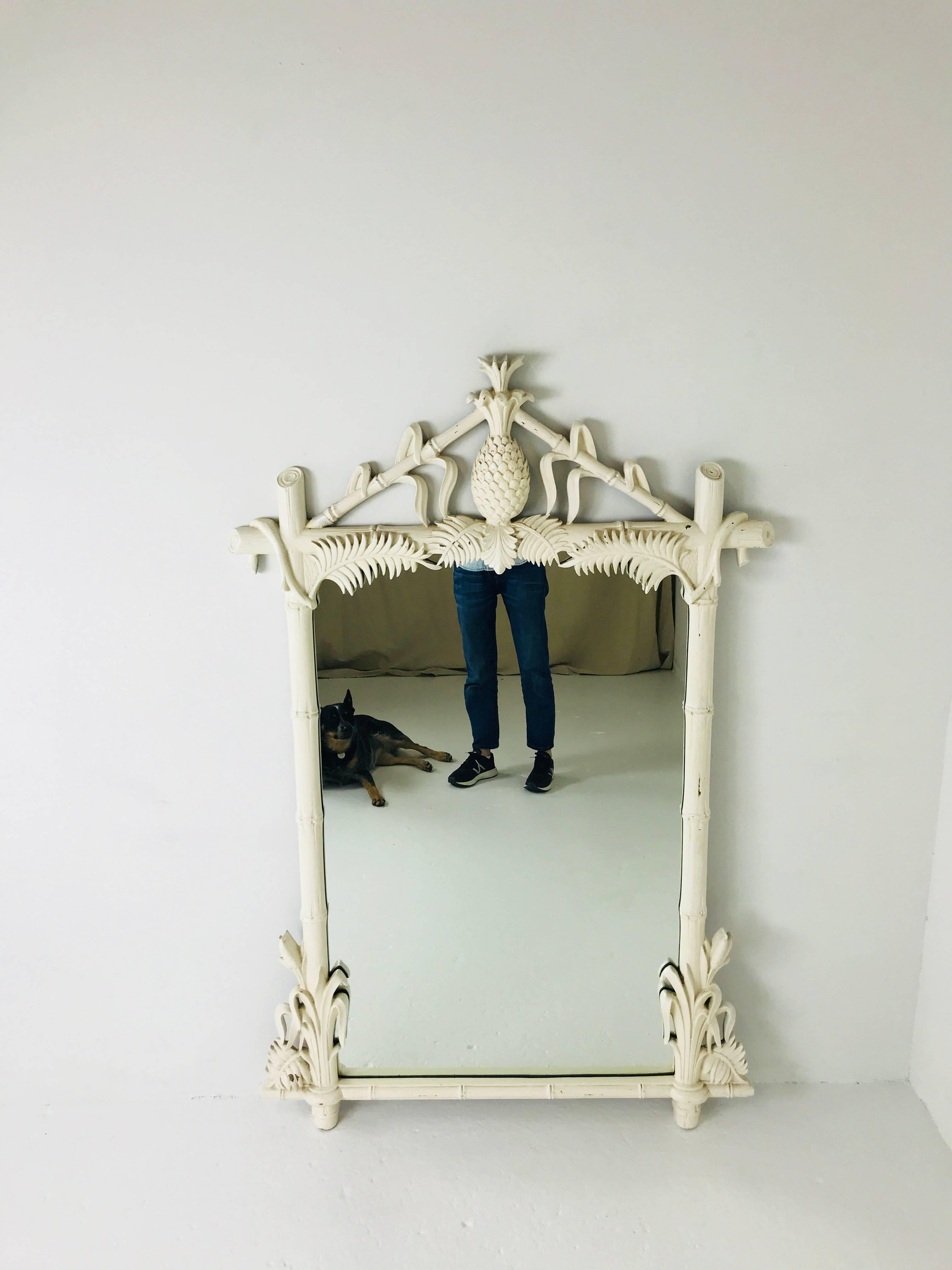Stunning Hollywood Regency lacquered Pineapple faux bamboo wall mirror by Gampel-Stoll. This Chinoiserie style mirror has a carved pineapple at top of mirror and palm frond leaves the lend to a more tropical feel. Mirror is in good vintage condition