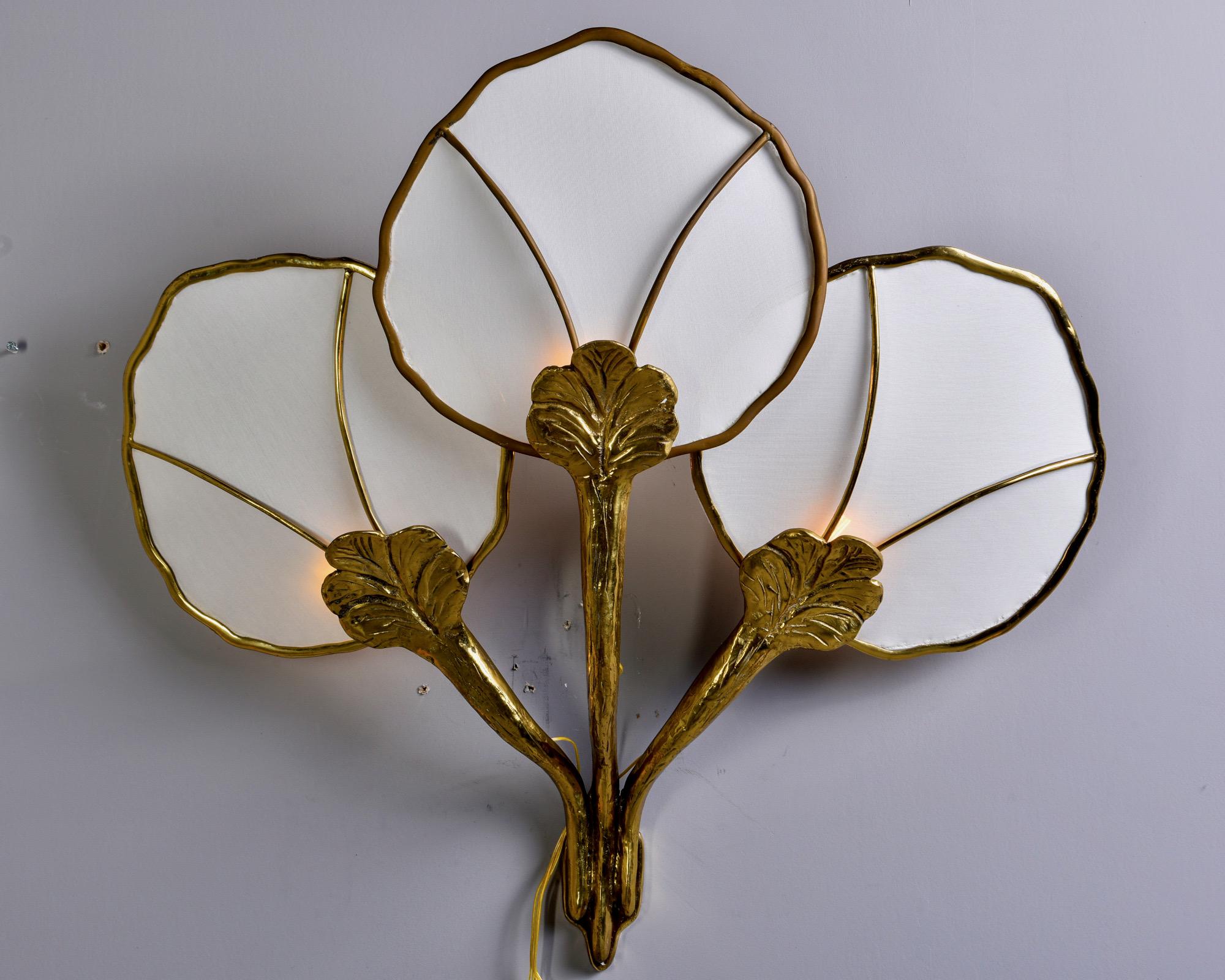 Extra large Hollywood Regency style wall lamp in form of water lily with brass base and white fabric shades in manner of Maison FlorArt, circa late 1960s. Three candelabra sized sockets. New wiring for US electrical standards. Found in Italy,