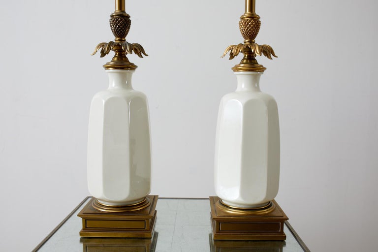 Pair of gorgeous Hollywood Regency Stiffel lamps with a Lenox porcelain vase form body and featuring a classic brass leafed pineapple spacer and pedestal. Original long brass torchiere style stem with a milk glass diffuser. The shaped Lenox bodies