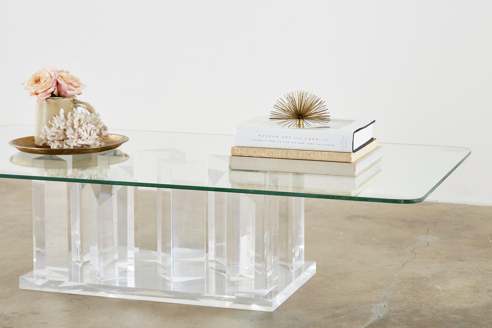 Fantastic Hollywood Regency coffee or cocktail table. Featuring a sculptural lucite base with facet cut stalagmite shape forms. The large rectangular pane of glass rests upon a bed of angular shapes that reflect and play with the reflections of