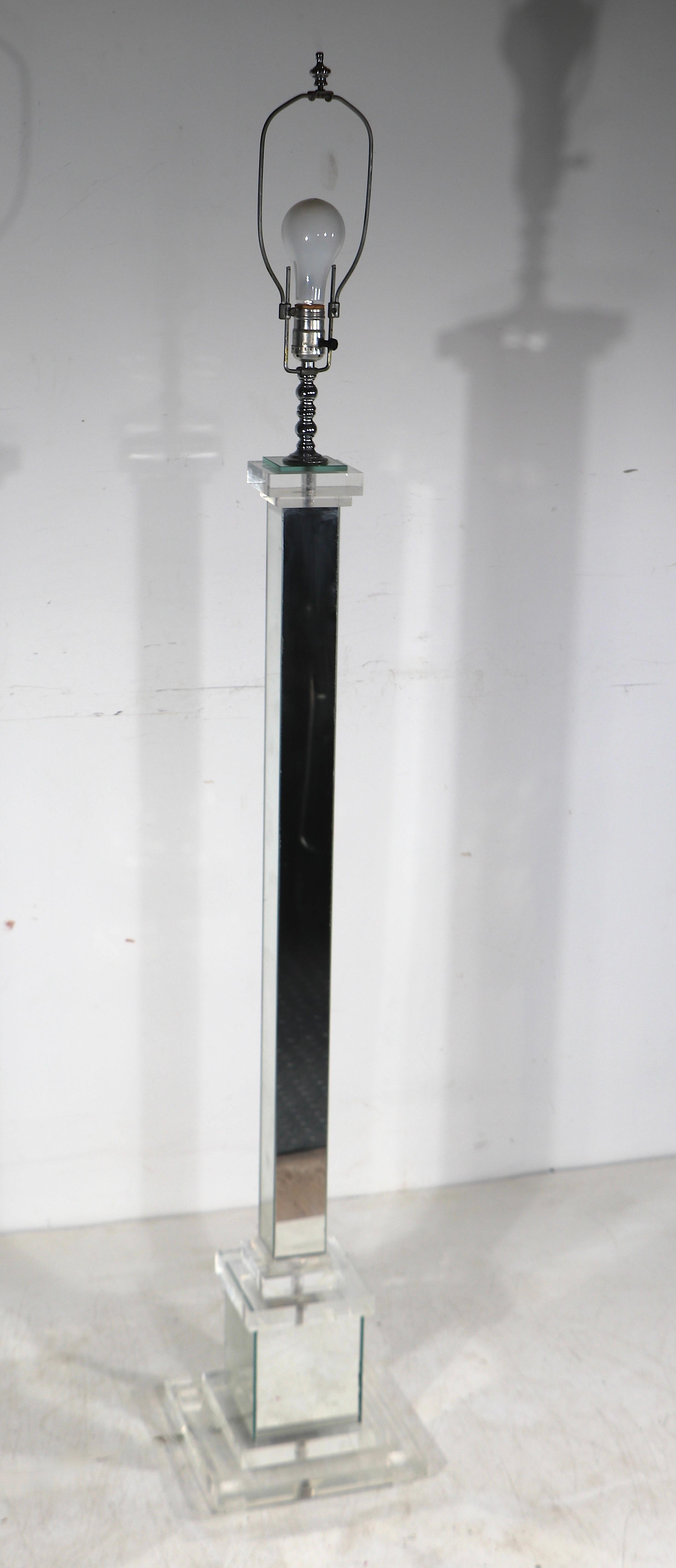 Exceptional Hollywood Regency  style floor lamp having a stepped lucite base, mirrored vertical post and lucite capitol. This chic lamp is ion very fine, clean, original and ready to use condition, showing only light wear, normal and consistent with