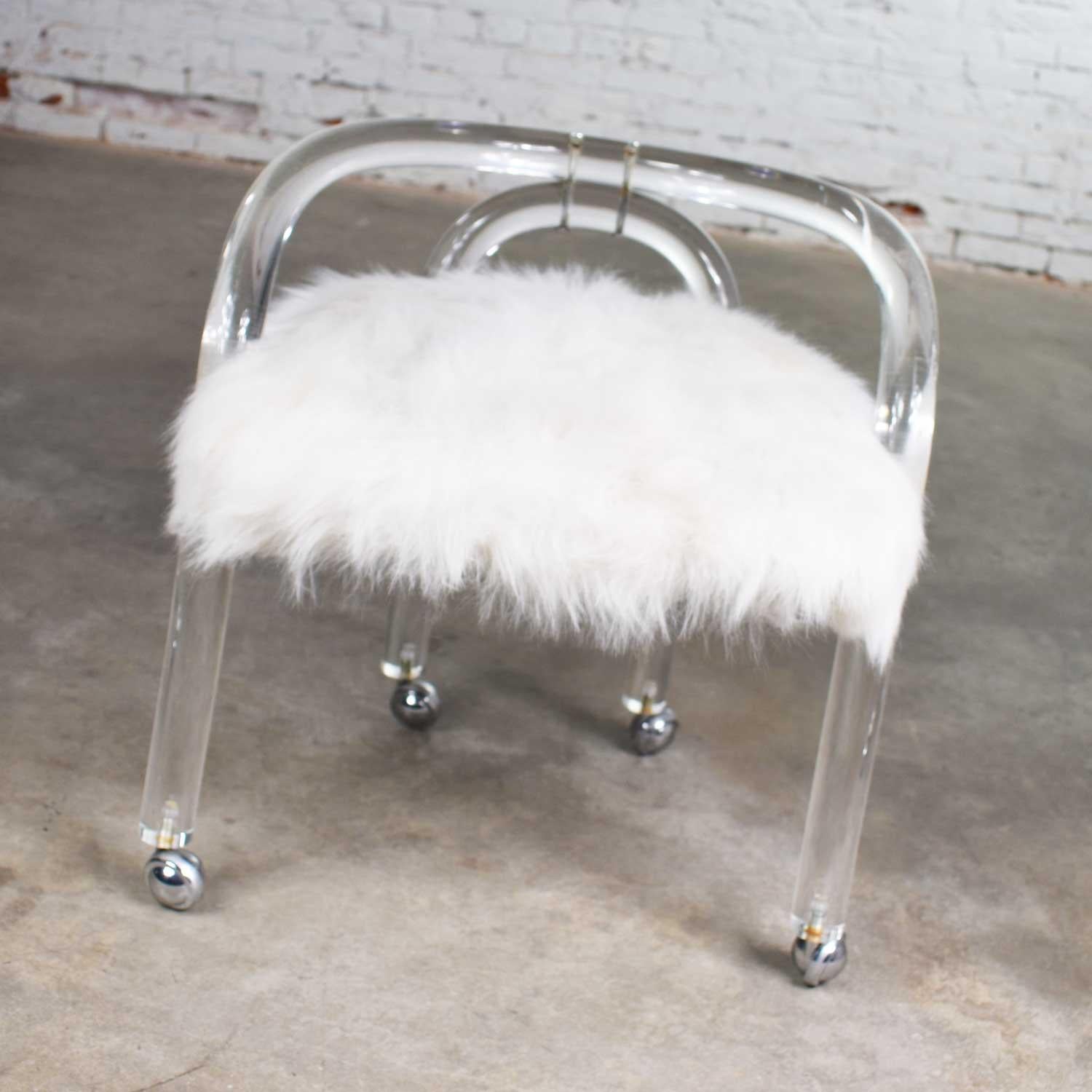 Extraordinary Hollywood Regency Lucite vanity stool in the style of Charles Hollis Jones upholstered in white faux fur and on casters. It is in wonderful vintage condition with no outstanding flaws we have detected. There is a small amount of