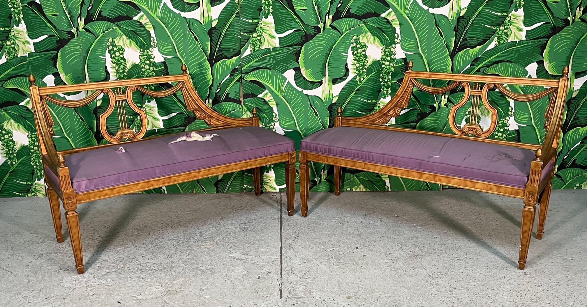 Pair of 1950s chaise benches in the style of Dorothy Draper feature hand carved wood frames with a lyre and draped fabric motif. Excellent structural condition with minor imperfections to finish, and cushions in need of reupholstering.
 