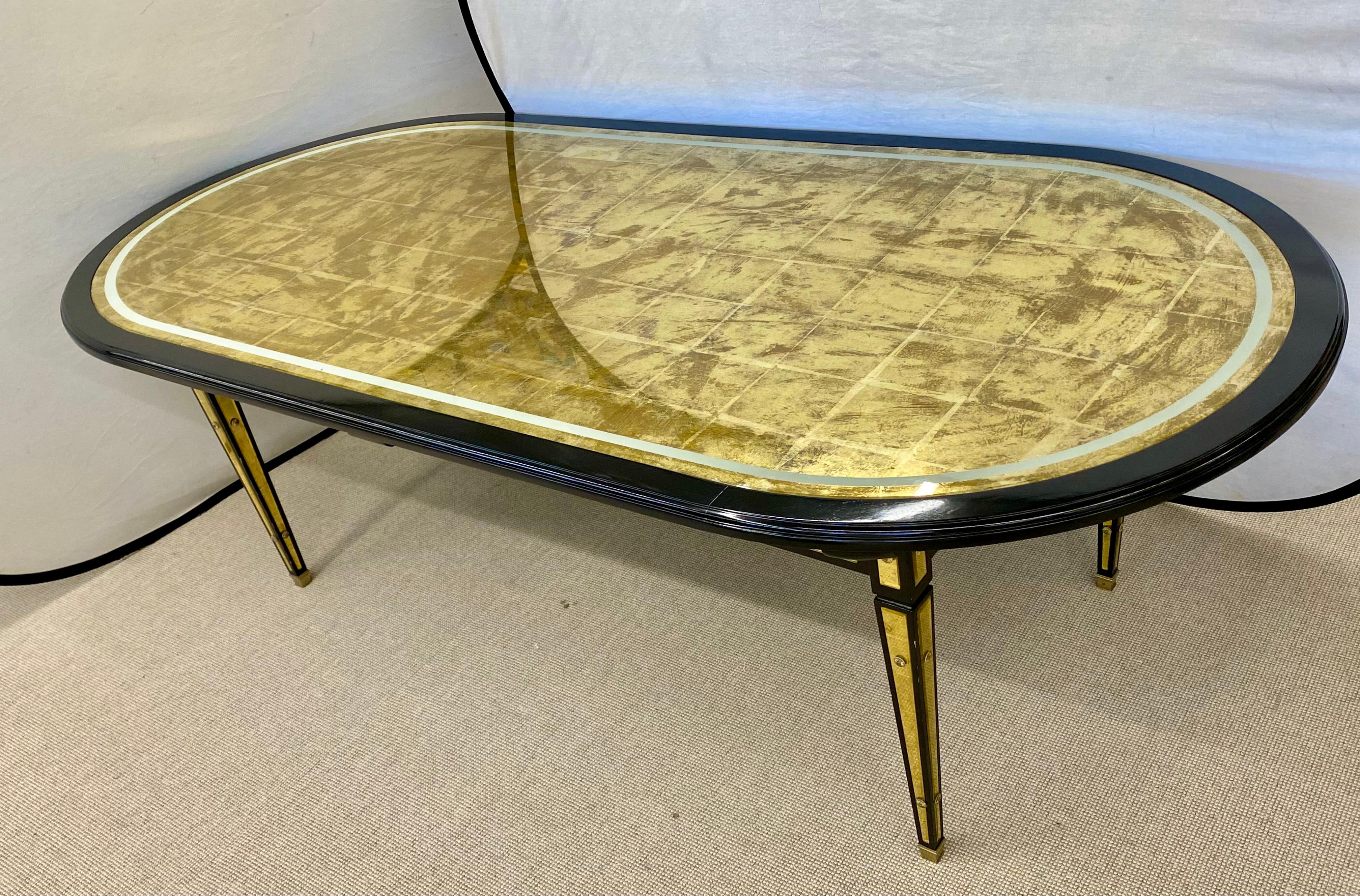 Hollywood Regency Maison Jansen dining table. Black lacquered with gilt eglomise glass having a silver eglomise border and brass trim. 20th century the whole having rounded rectangular top raised on tapered triangular section legs, applied with