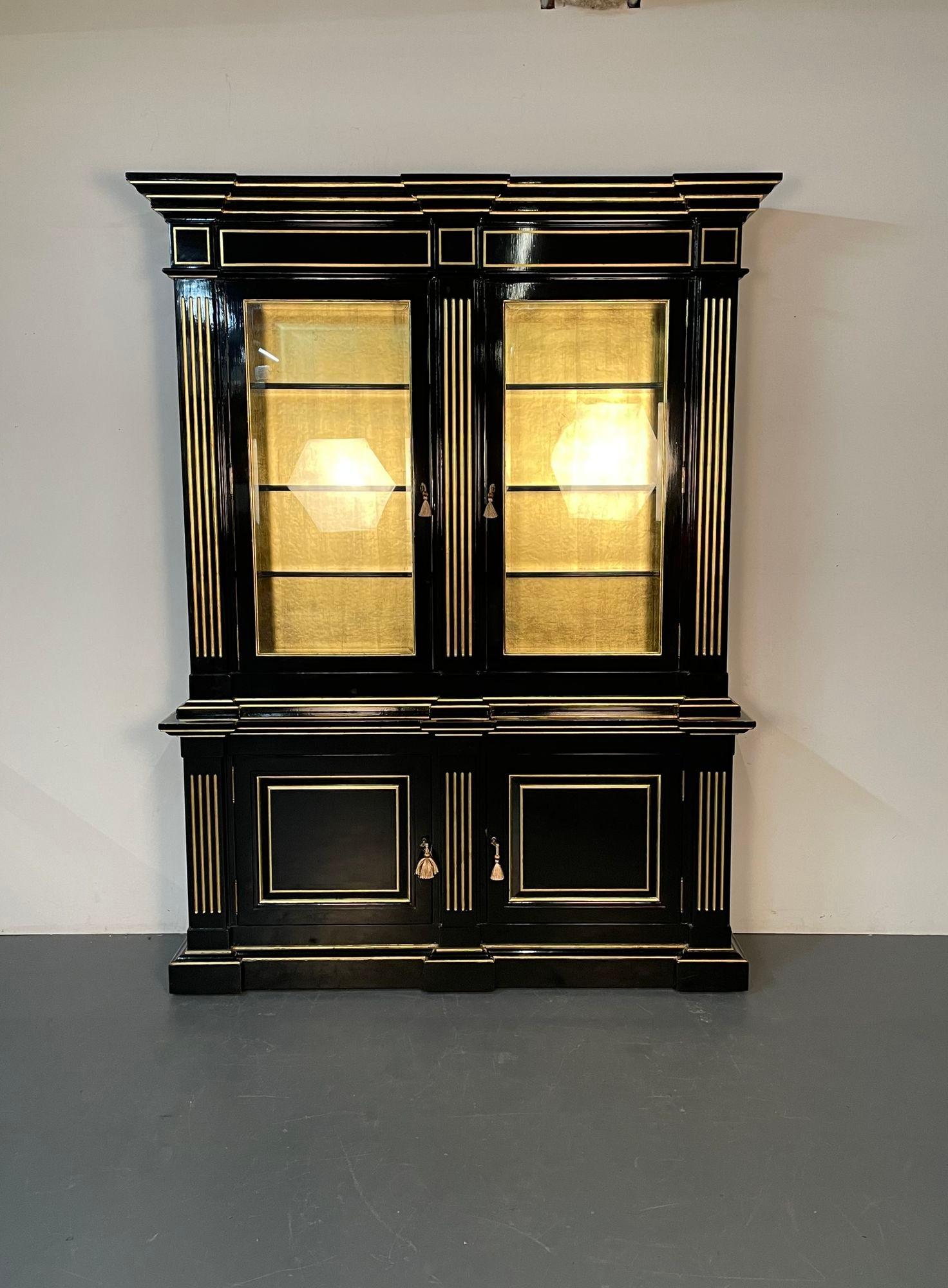 Hollywood Regency Maison Jansen Style Bookcase / China Cabinet, Ebony, Gold Leaf
 
A stunning refinished cabinet having two beveled glass doors leading onto a gilt leaf backing under a lighted interior. The thin sleek top with gilt reeded design