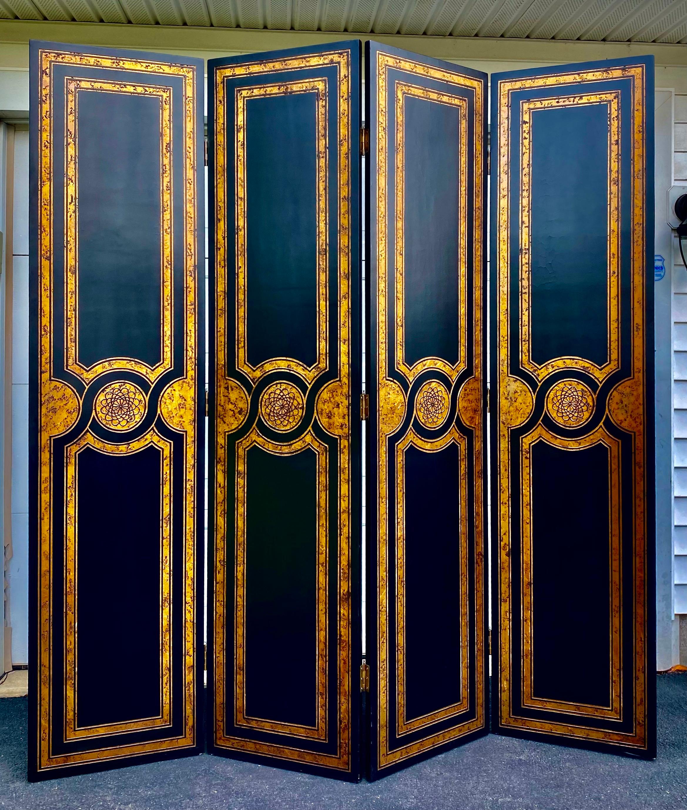 Large Hollywood Regency style four panel decorative floor screen. This tall room divider features a black and gold tortoise-like finish with carved medallions and border details. Back side is solid black. In the style of Maitland Smith.